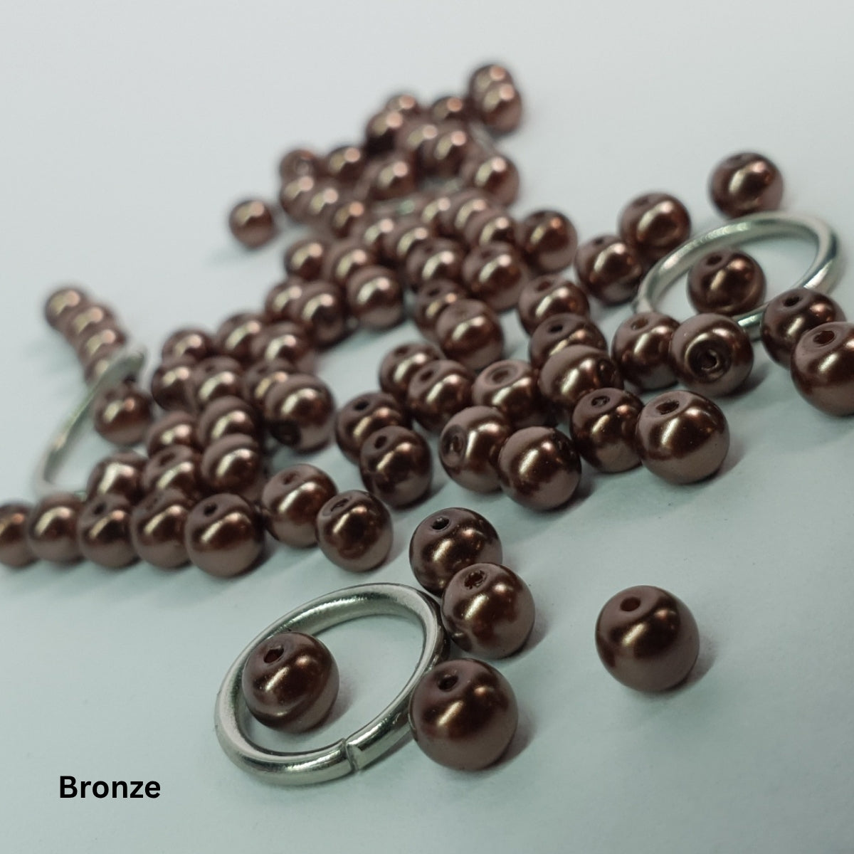 Close-up of warm bronze-stone glass pearls set within stainless steel chainmail.