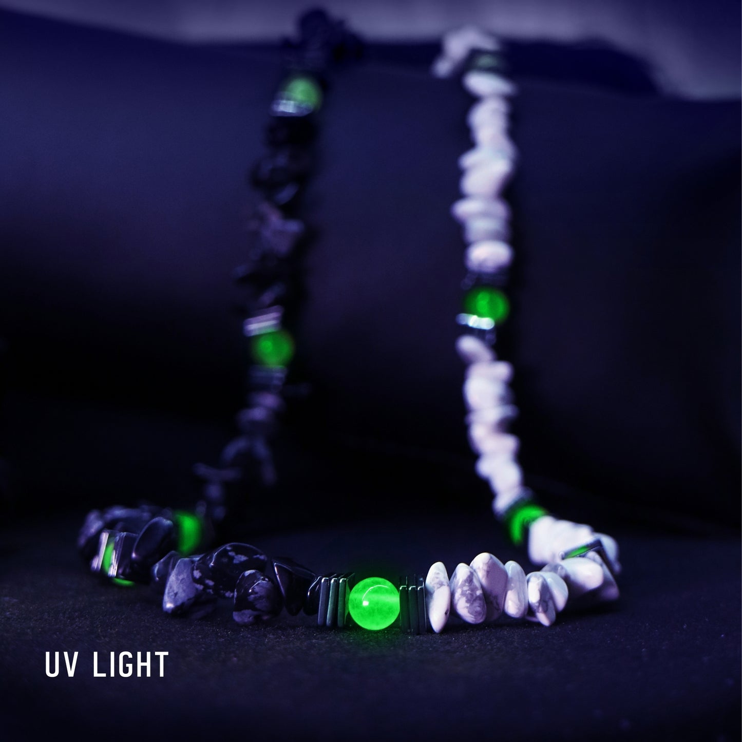 Full view of the black and white natural stone necklace under UV light, showing the central neon green UV-reactive beads.