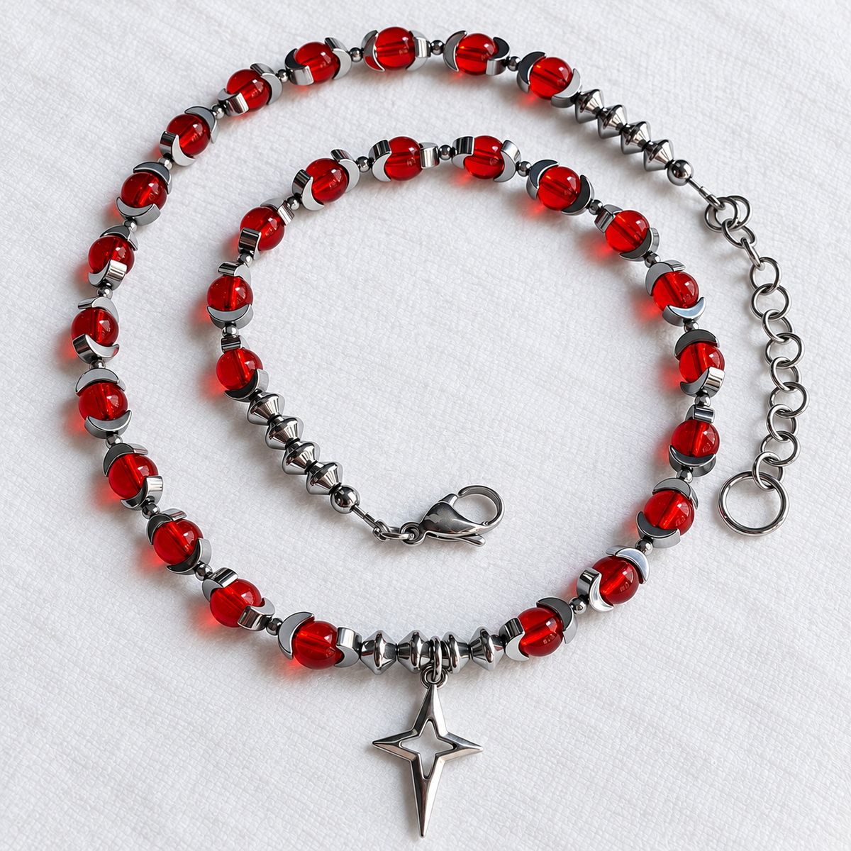 CELESTIA necklace showing red glass beads, half-moon hematite, silver North Star pendant and clasp.