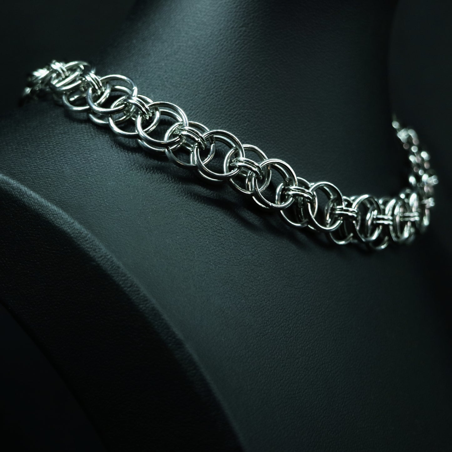 Angled close-up of a stainless steel chainmail choker featuring interlocking round rings and a reflective linked pattern.