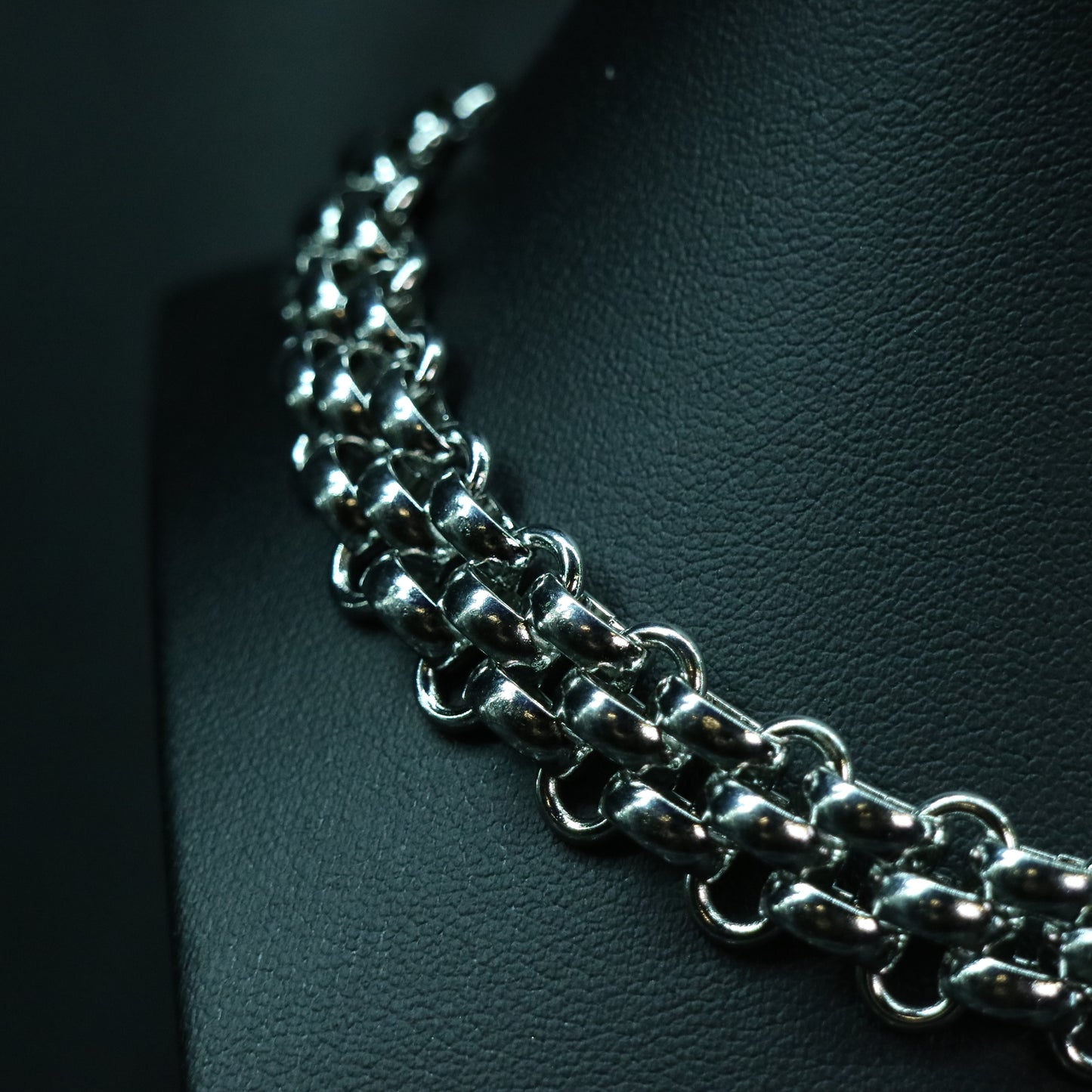 Angled view of a stainless steel flat weave chain sitting close to the neck with reflective interlocked links.