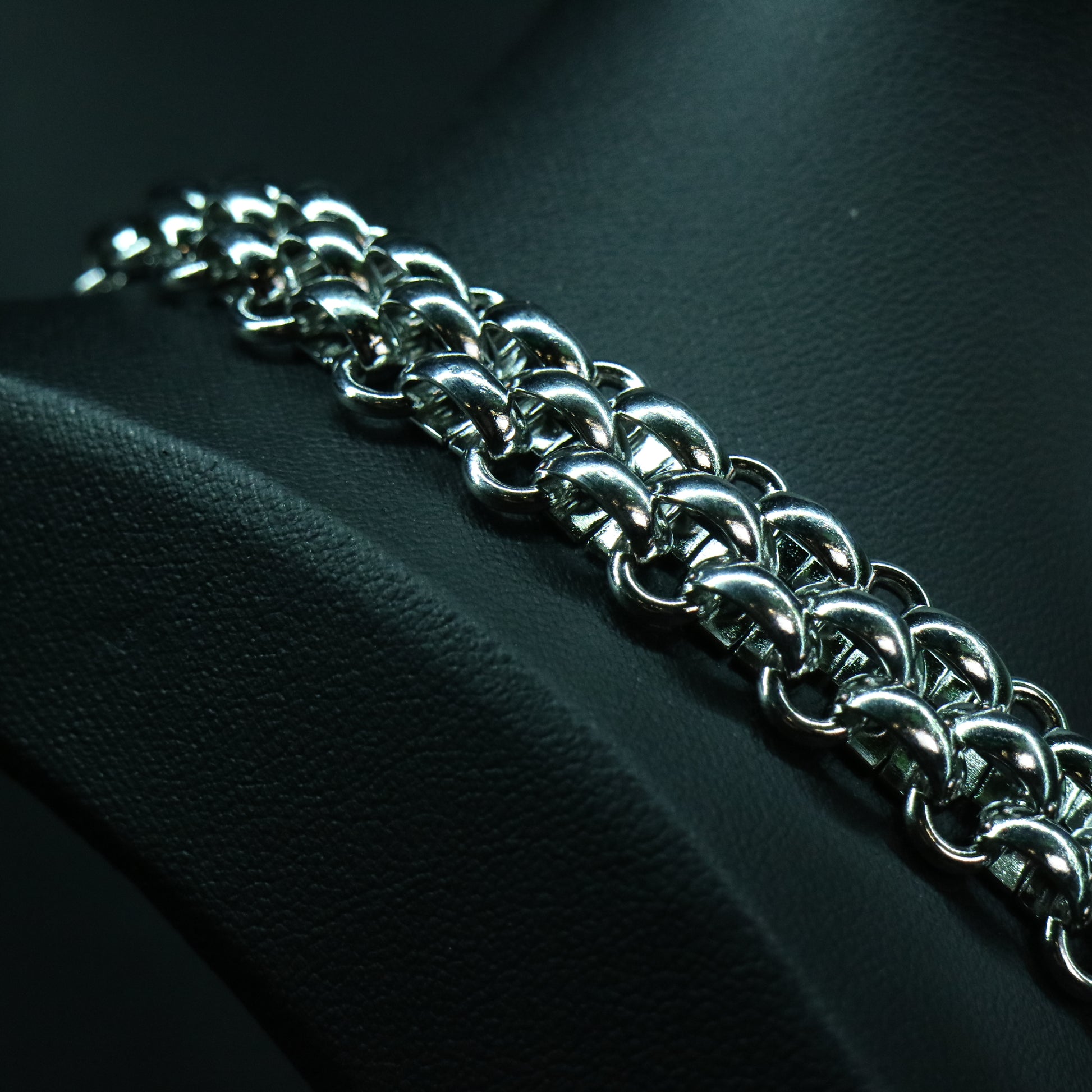 Close-up of a stainless steel flat weave chain showing its low-profile interlocked link pattern