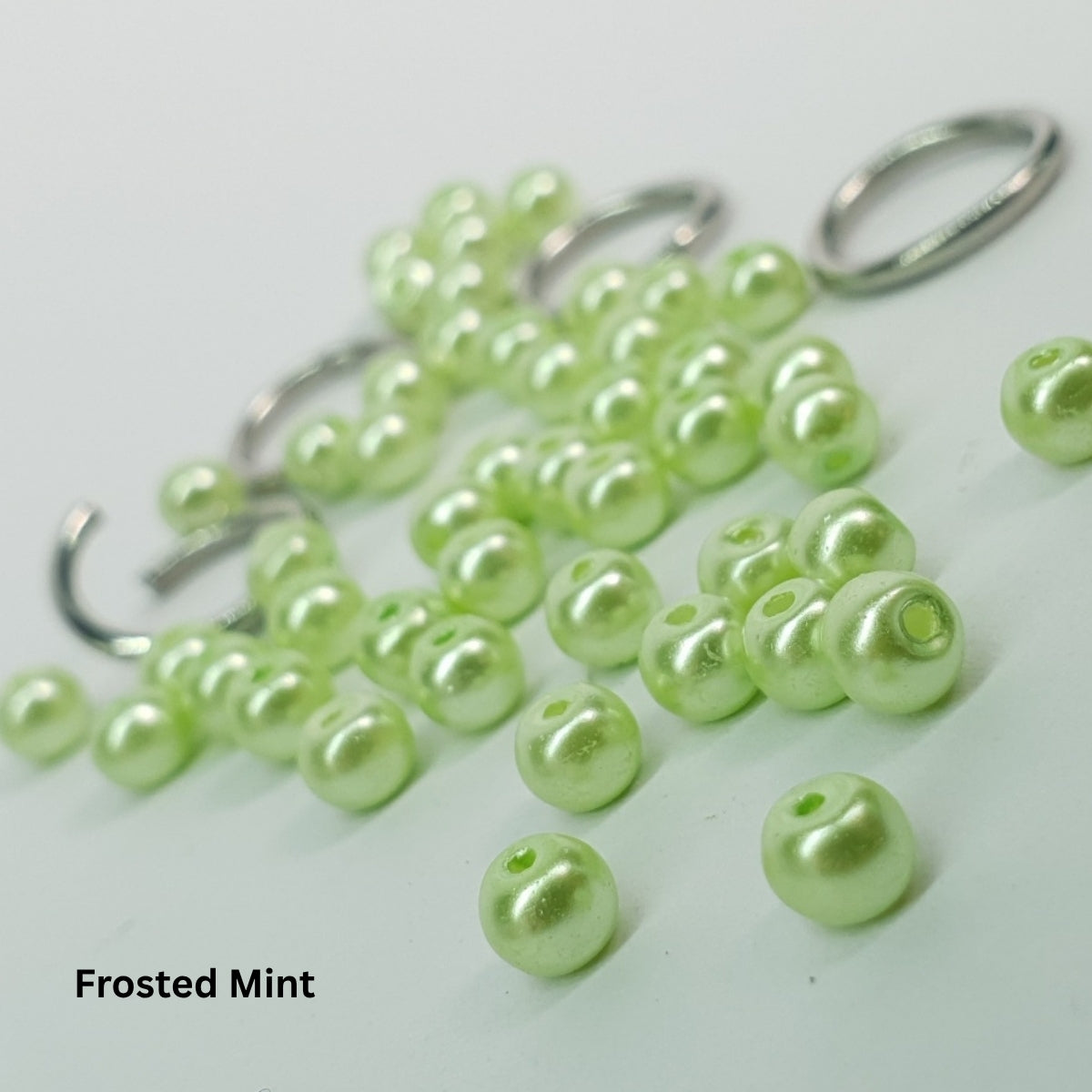 Close-up of frosted mint-green glass pearls paired with stainless steel chainmail rings.