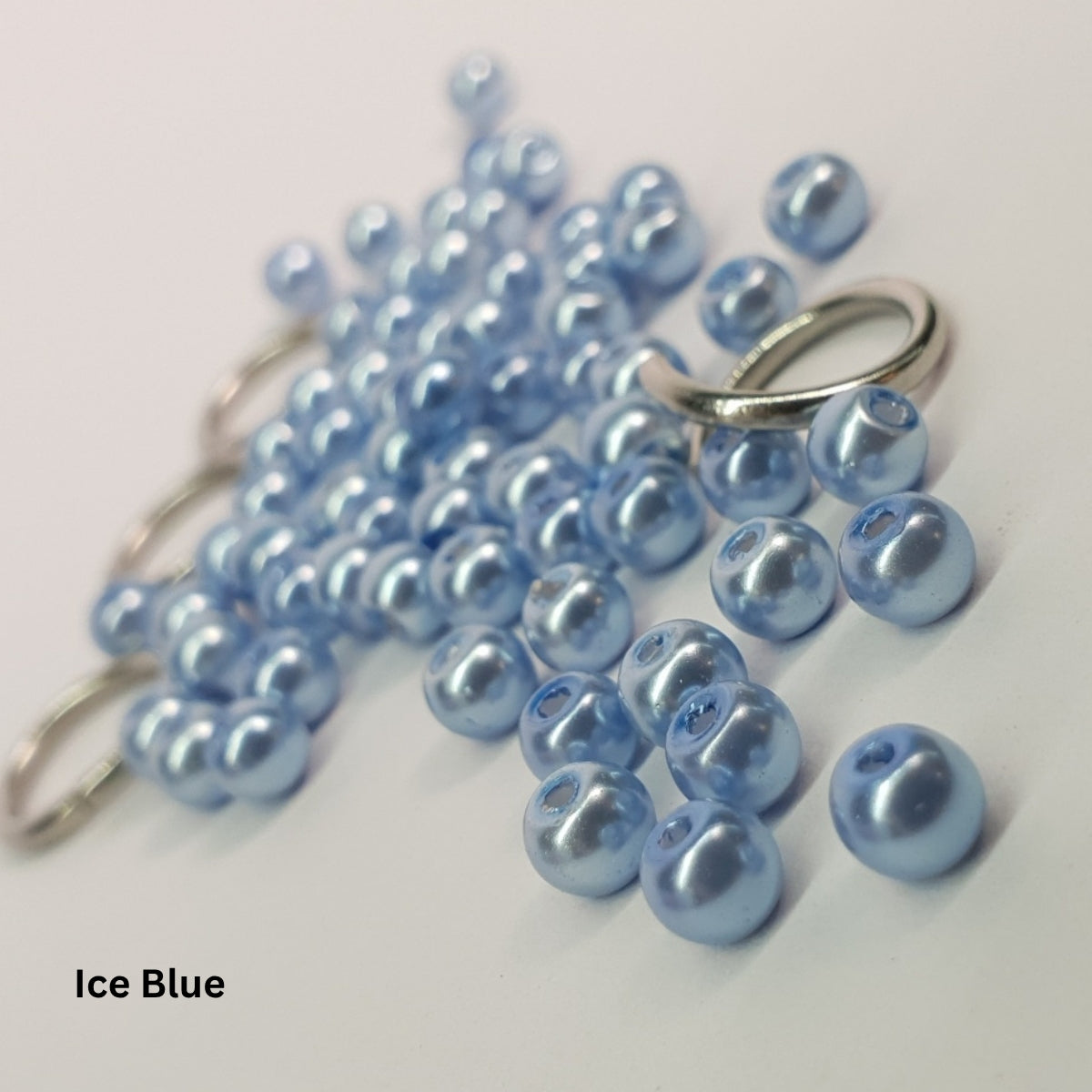 Close-up of frosty ice-blue glass pearls paired with stainless steel chainmail rings.