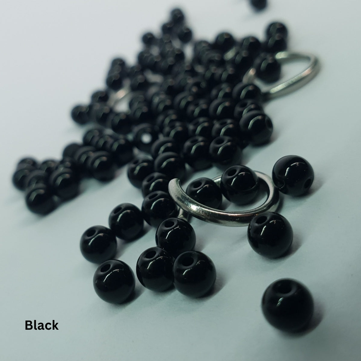 Close-up of glossy black glass pearls woven into stainless steel chainmail links.

4. Gunmetal Pearl