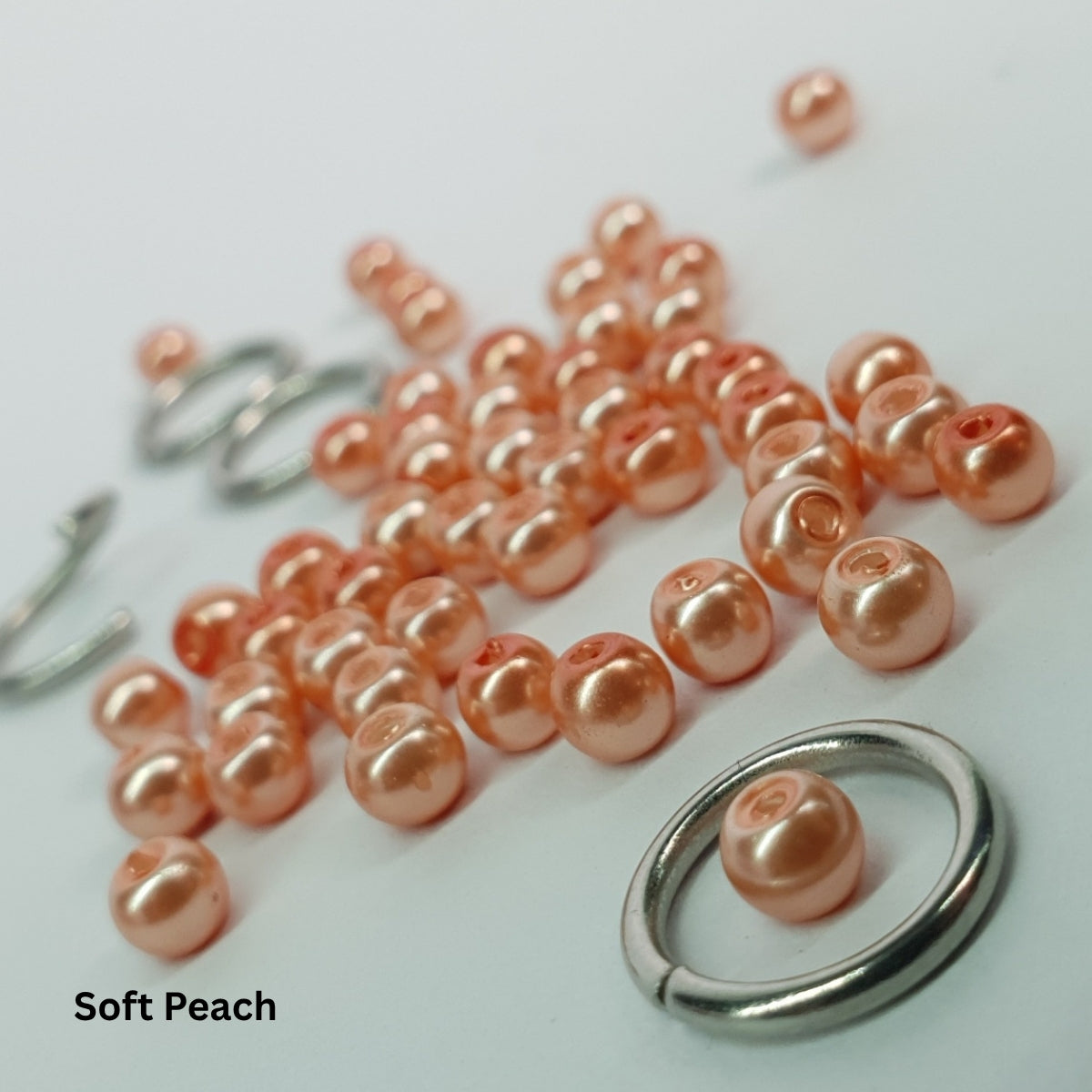Close-up of light soft-peach glass pearls set inside stainless steel chainmail links.
