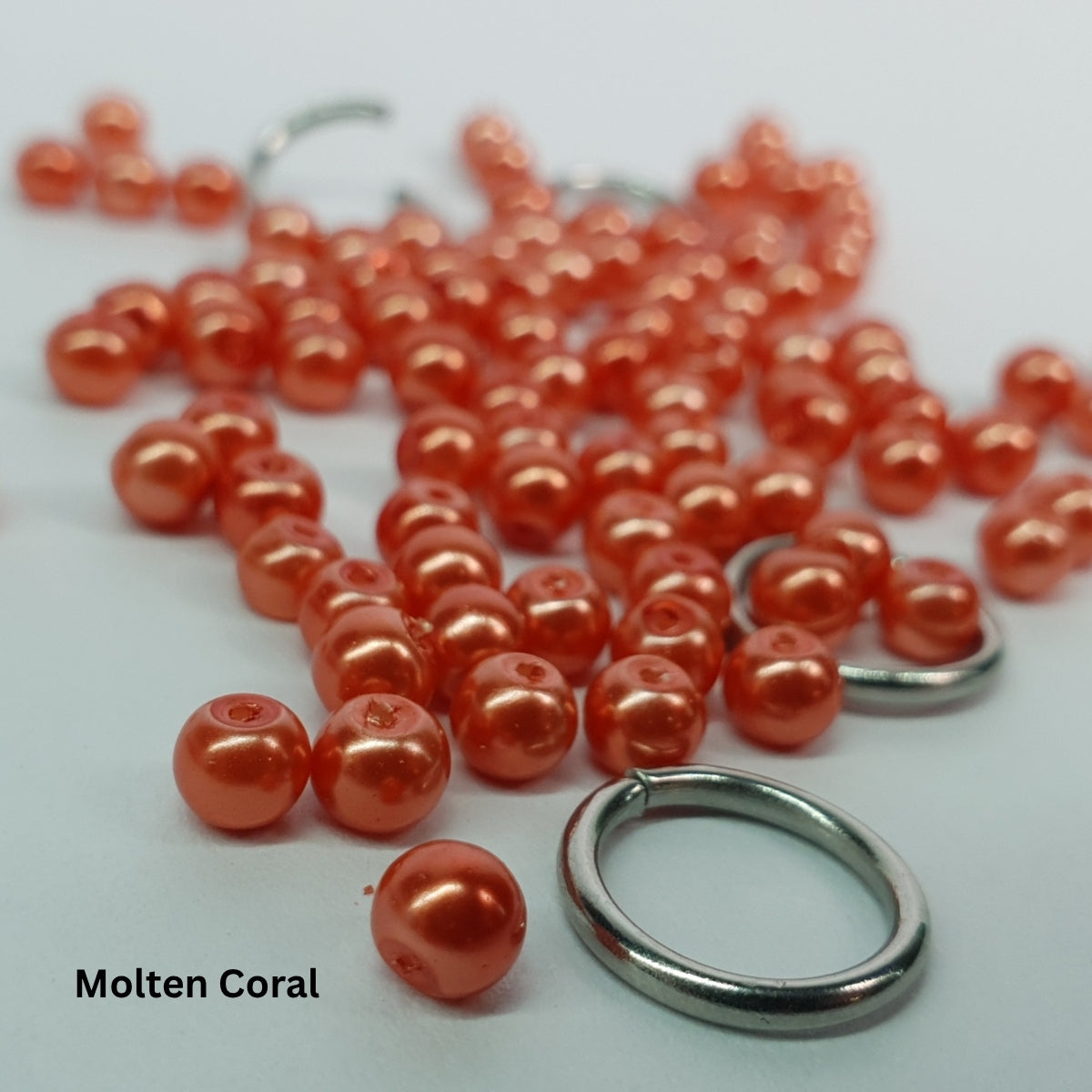 Close-up of molten-coral glass pearls woven into stainless steel chainmail.