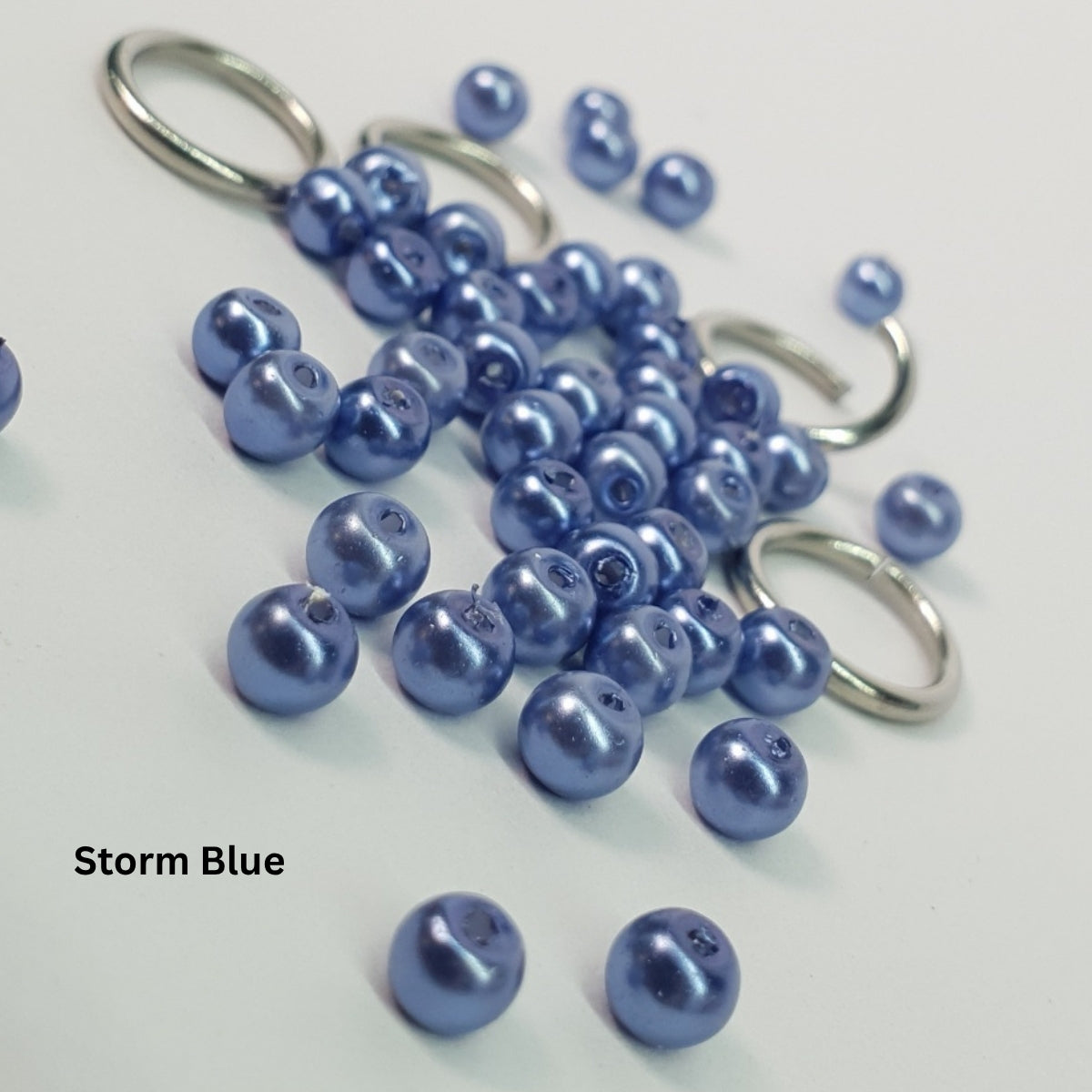 Close-up of muted storm-blue glass pearls woven into stainless steel chainmail.