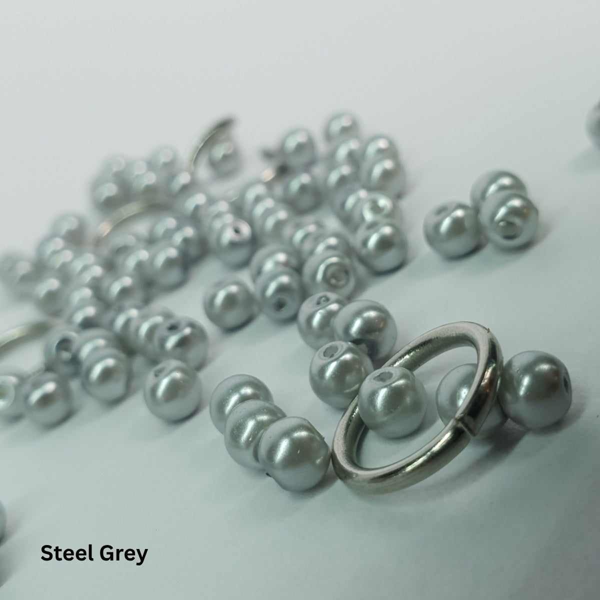 Close-up of pale steel-grey glass pearls set within stainless steel chainmail links.