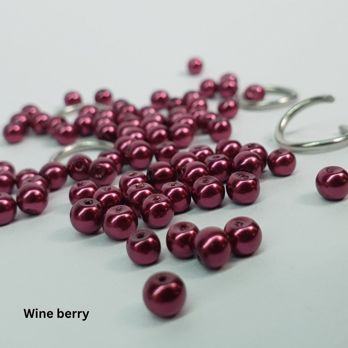 Close-up of rich wine-berry glass pearls paired with stainless steel chainmail links.