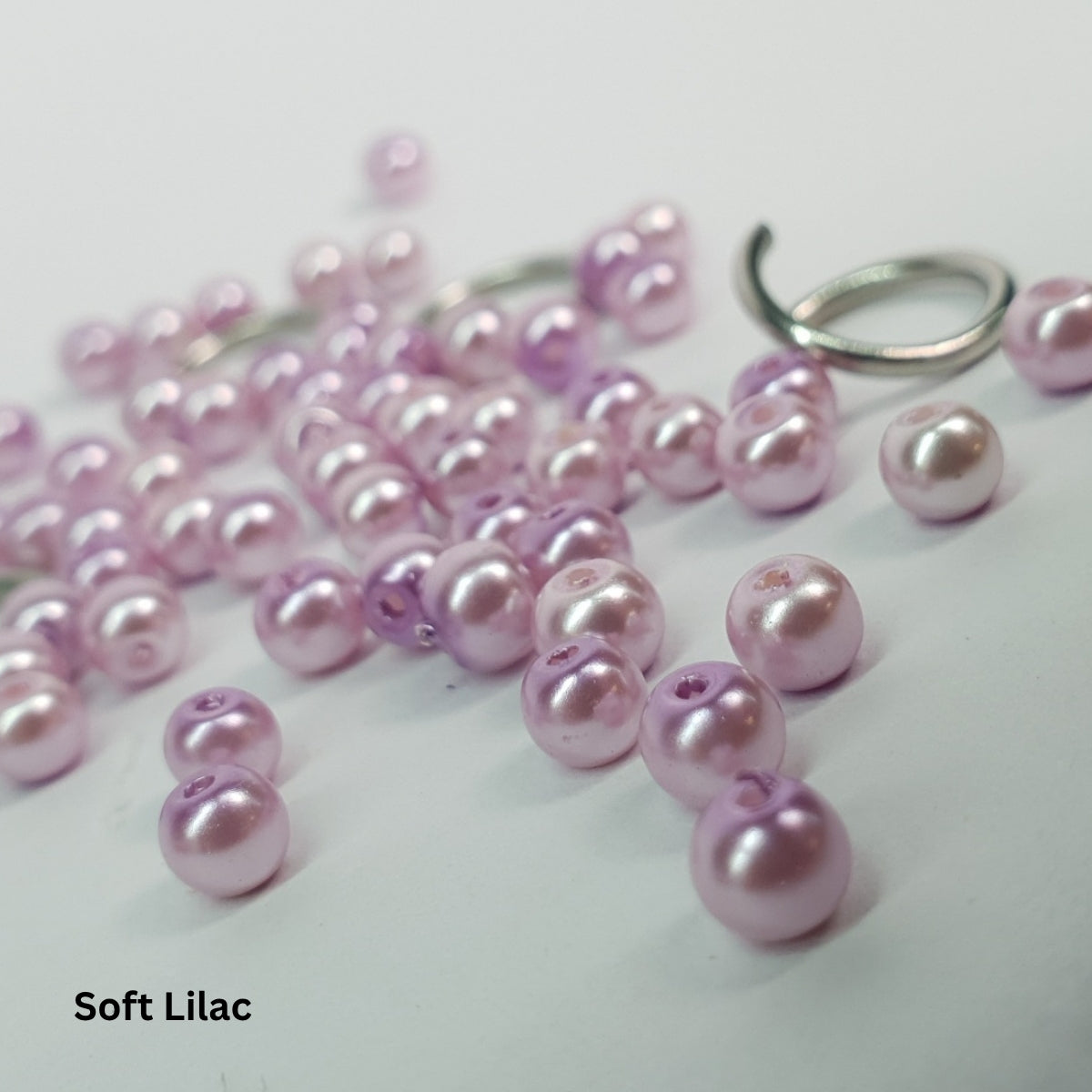 Close-up of soft lilac glass pearls woven into stainless steel chainmail.
