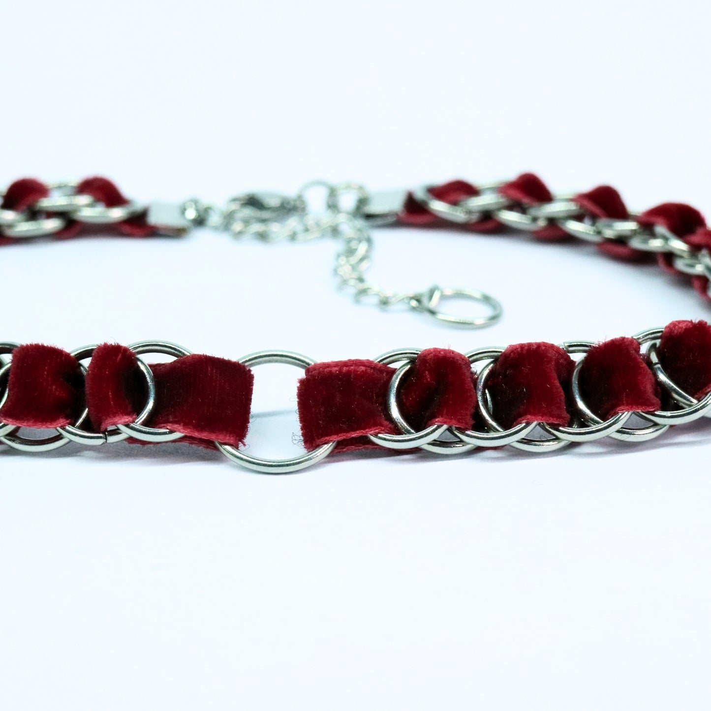 Close-up of the blood red velvet ribbon woven through stainless steel rings with the O-ring centerpiece.