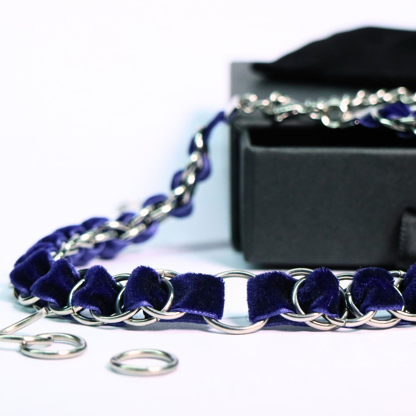 Close-up of the deep blue velvet ribbon choker with stainless steel ring links and an O-ring center on a white background.