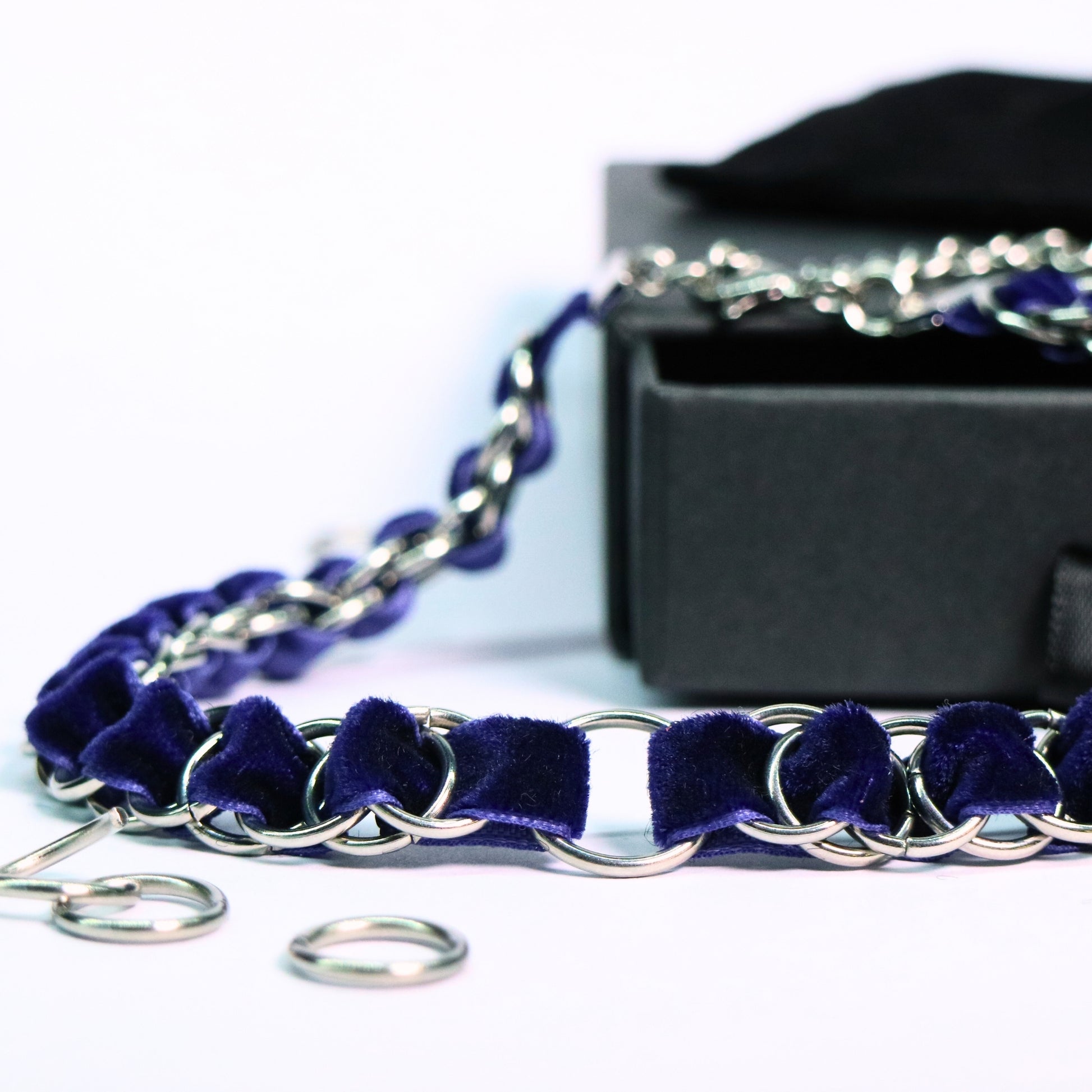 Close-up of the deep blue velvet ribbon choker with stainless steel ring links and an O-ring center on a white background.