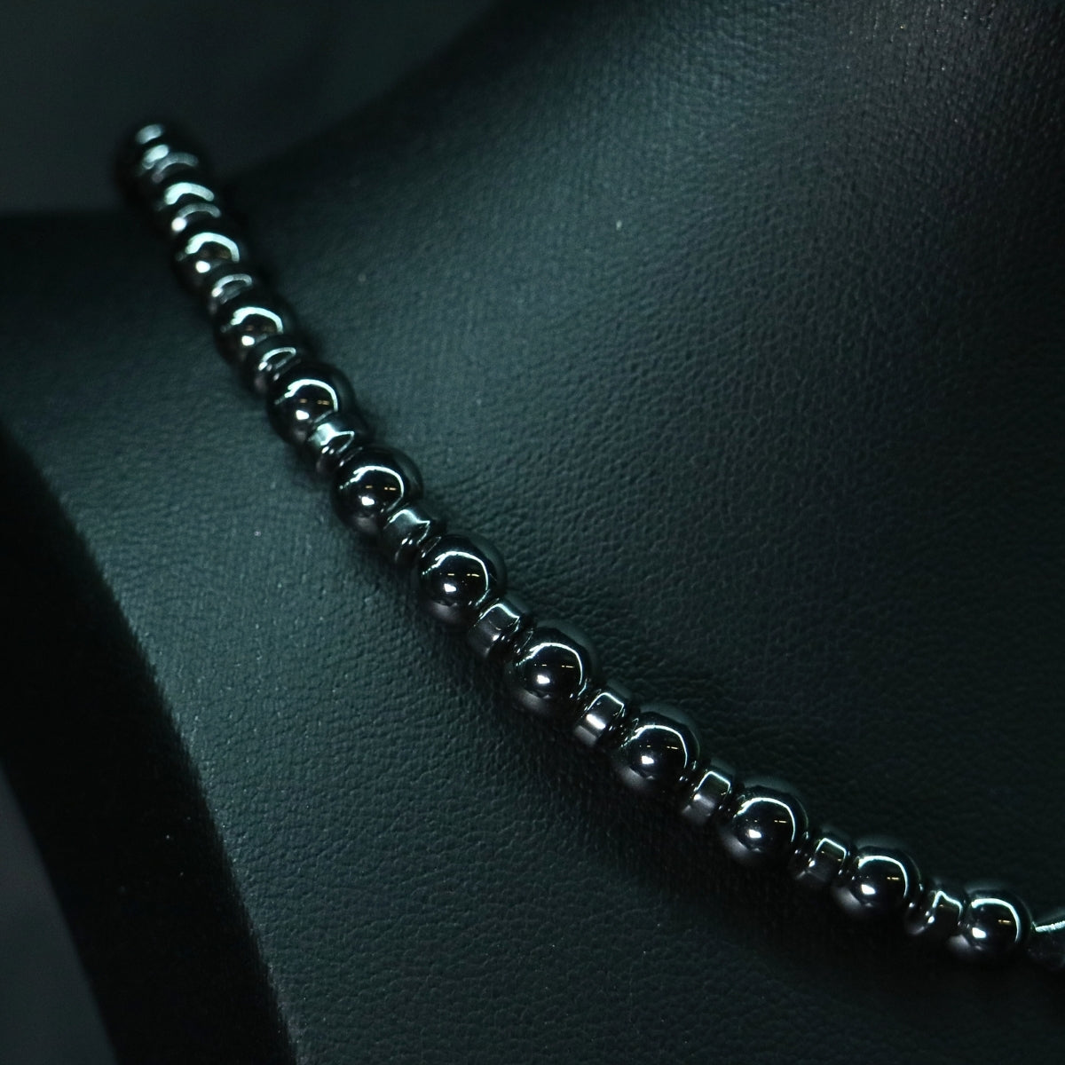 Detail shot of the stainless steel chainmail boxchain pattern and O-ring surrounded by white natural stones and hematite beads.