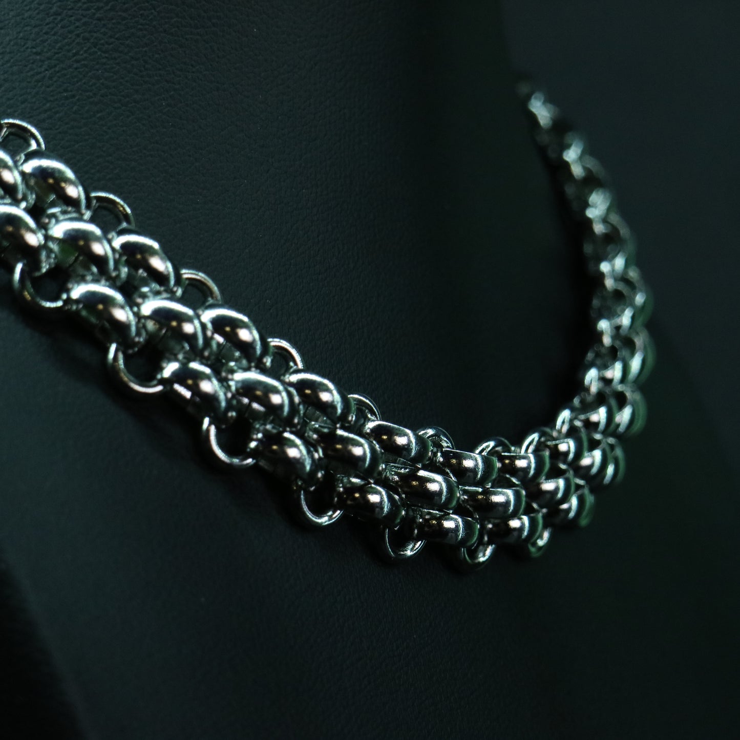 Detailed close-up of the stainless steel flat weave chain highlighting its smooth, armor-like linked structure.