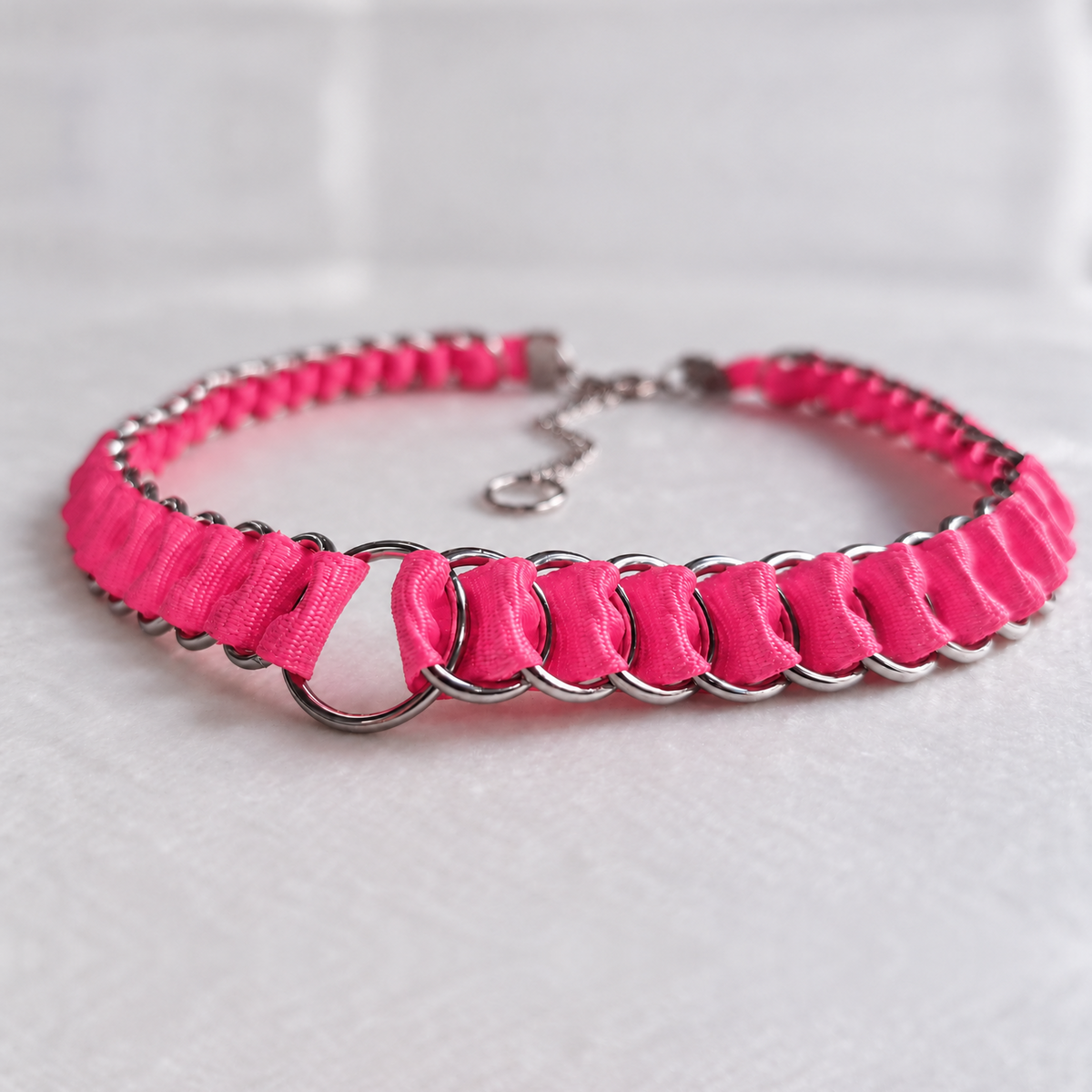 Full LOOM Barbie Pink fabric ribbon chainmail choker in a low front view, with stainless steel rings and a central O-ring on white fabric.