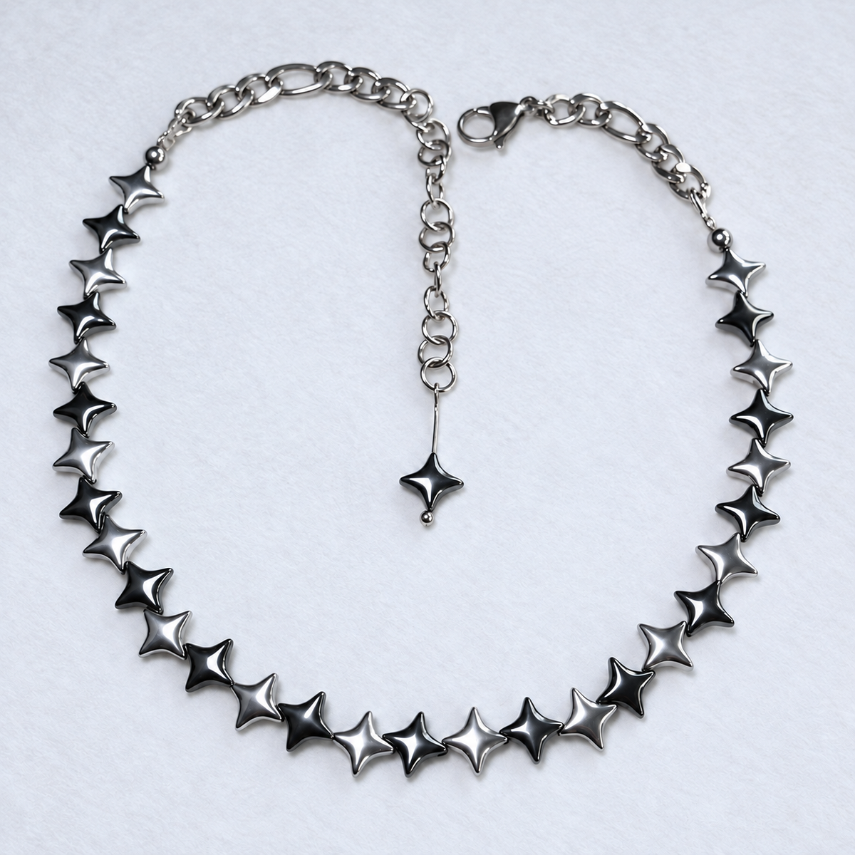 NORTHLINE Mixed North Star hematite choker with alternating silver and gunmetal beads and stainless steel chains on white fabric.