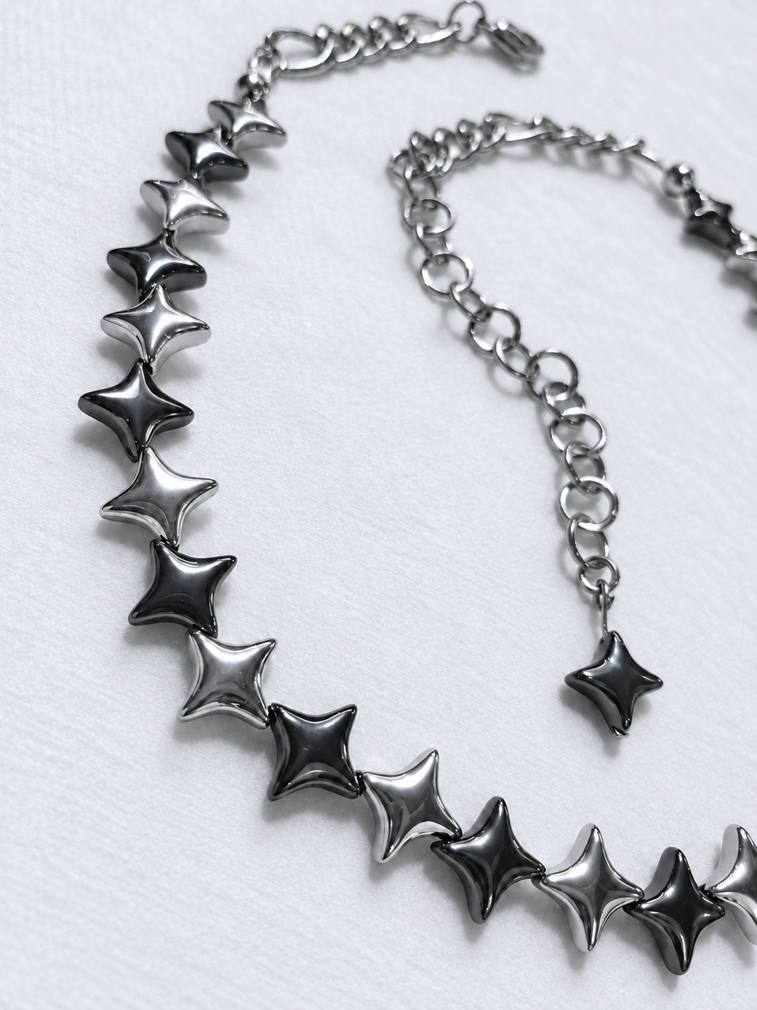 Close-up of alternating polished silver and gunmetal North Star hematite beads on NORTHLINE Mixed, with stainless steel rear chains and star-tipped extension.