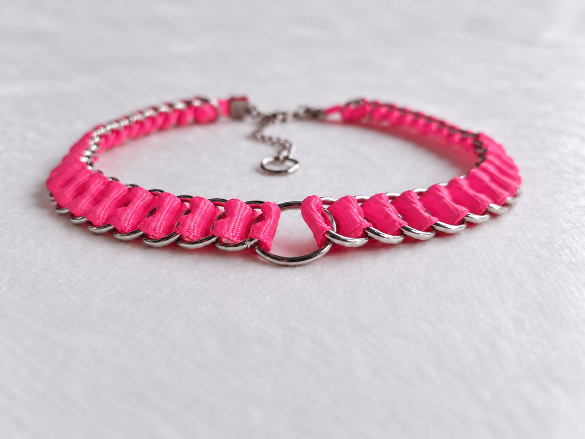 Angled view of the LOOM Barbie Pink ribbon chainmail choker showing folded ribbon, interlinked stainless steel rings and the central O-ring.
