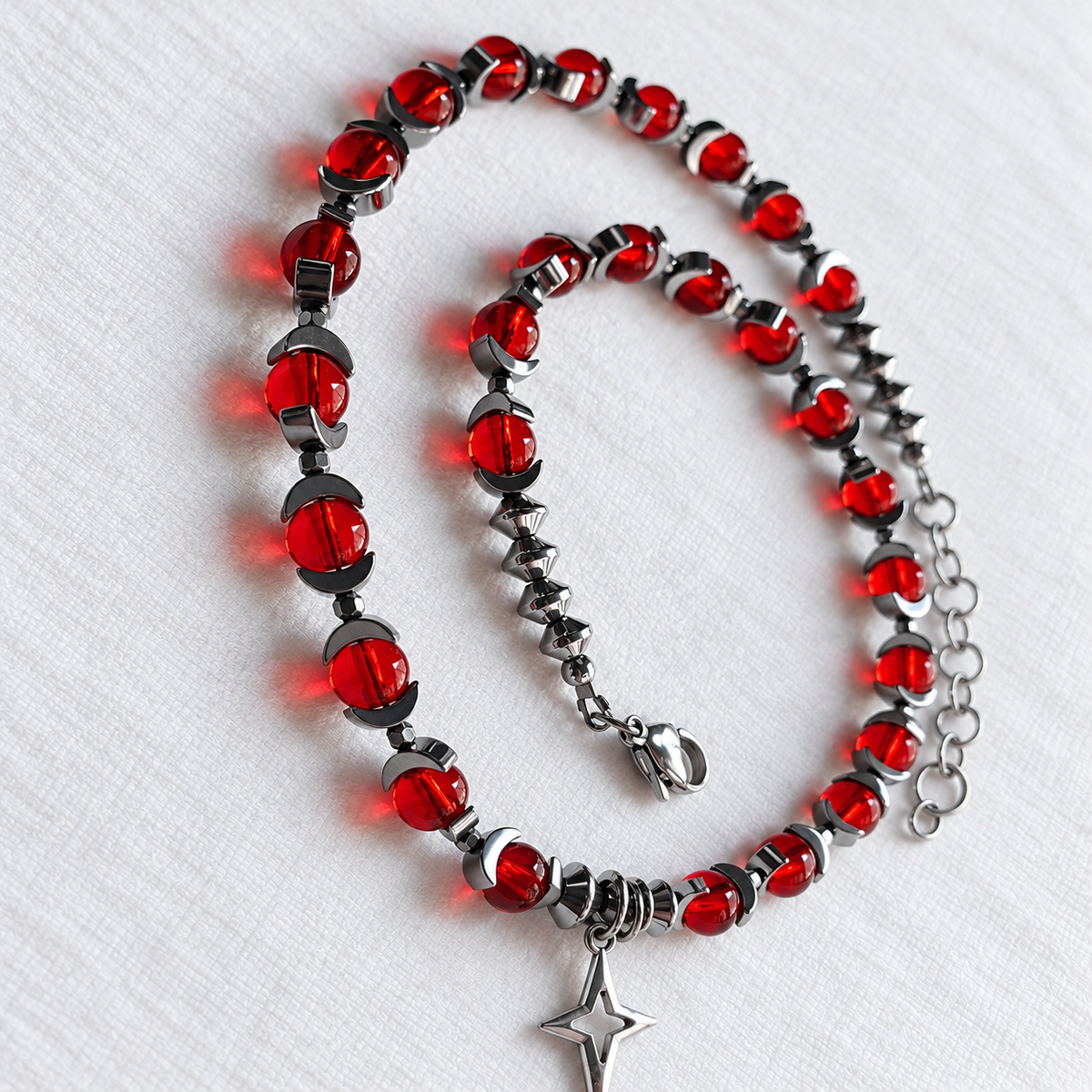 Angled detail of CELESTIA red glass beads and crescent hematite spacers.