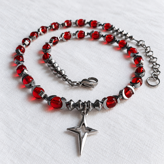 Low-angle view of CELESTIA red glass necklace with silver hematite beads and hollow North Star pendant.
