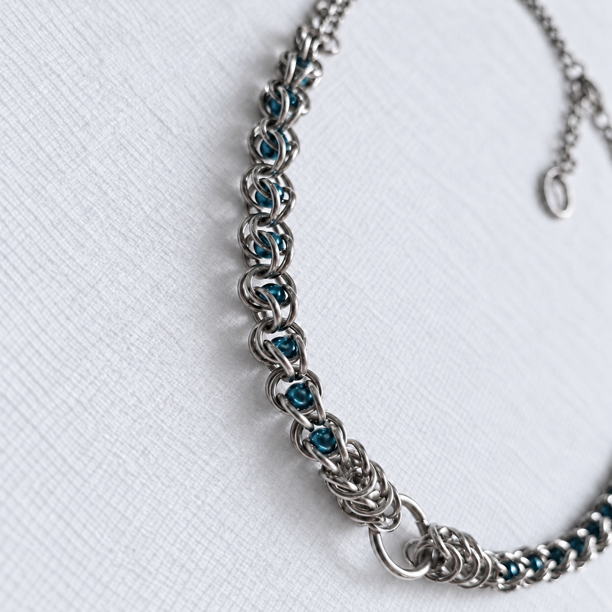 Angled view of ECHO teal glass pearl chainmail choker and front O-ring.