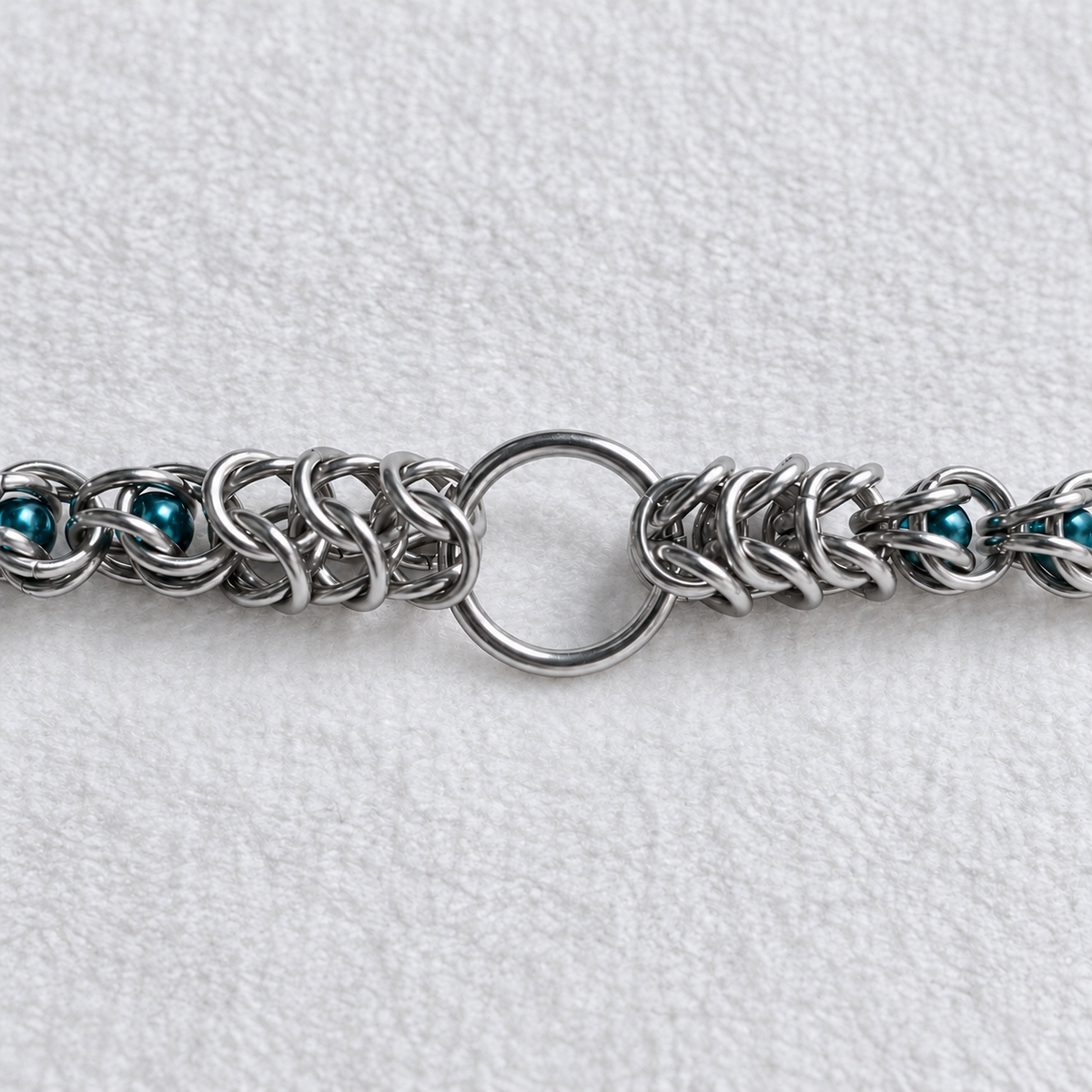 Close-up of ECHO's stainless steel front O-ring and chainmail weave with teal glass pearls.