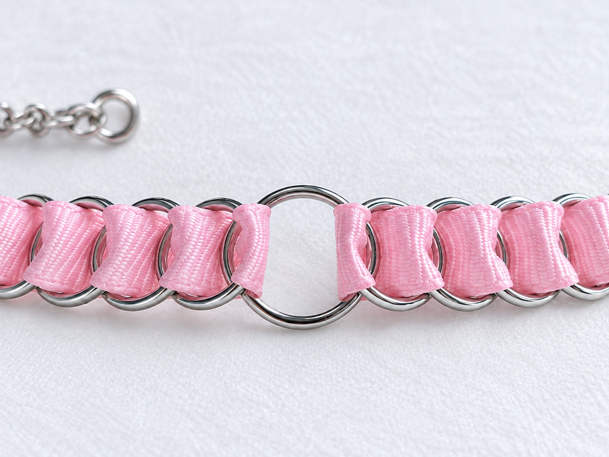 Close-up of baby pink ribbon woven through stainless steel rings and the central O-ring on the LOOM choker.