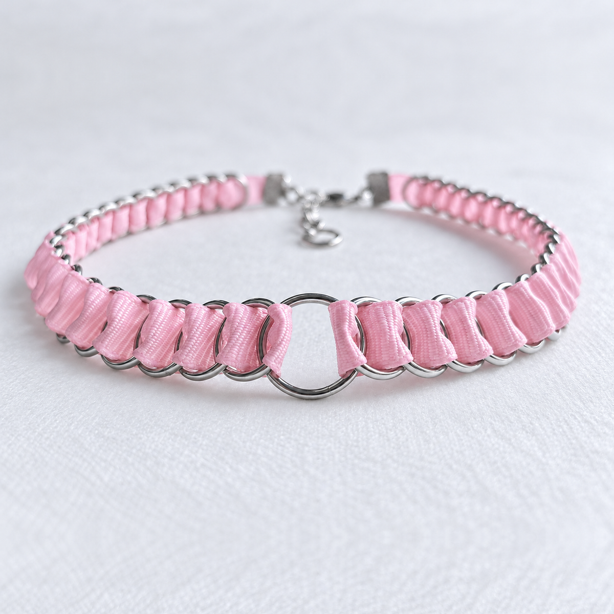 Full LOOM baby pink fabric ribbon chainmail choker in a curved low-angle view, with stainless steel rings and central O-ring.