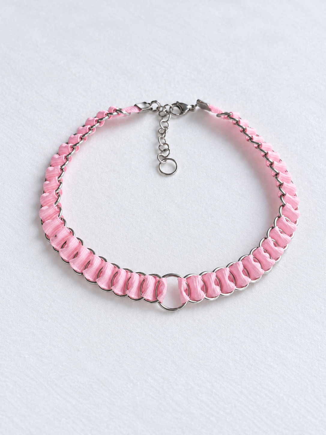 Full overhead view of the LOOM baby pink ribbon chainmail choker with central O-ring and adjustable fastening.