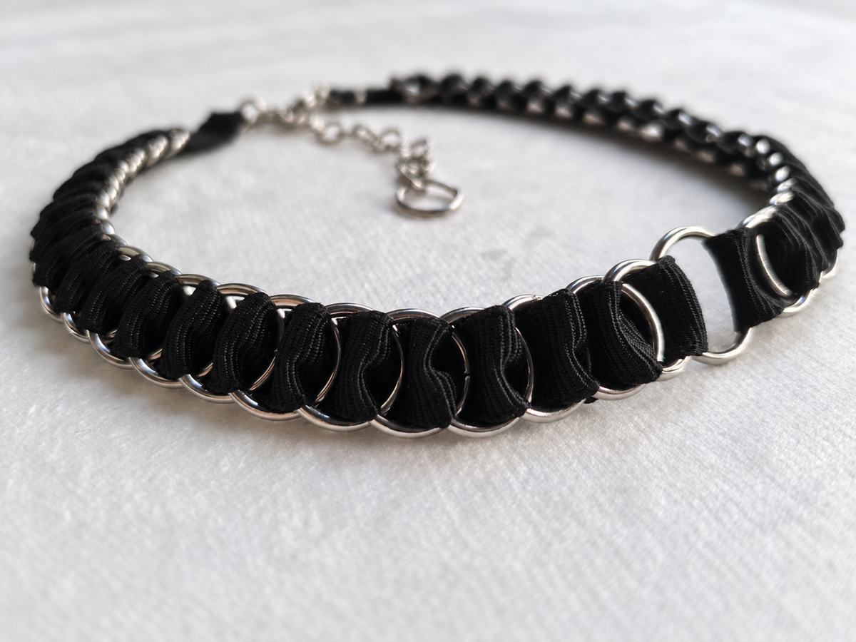 Angled view of black fabric ribbon woven through stainless steel rings on the LOOM choker.