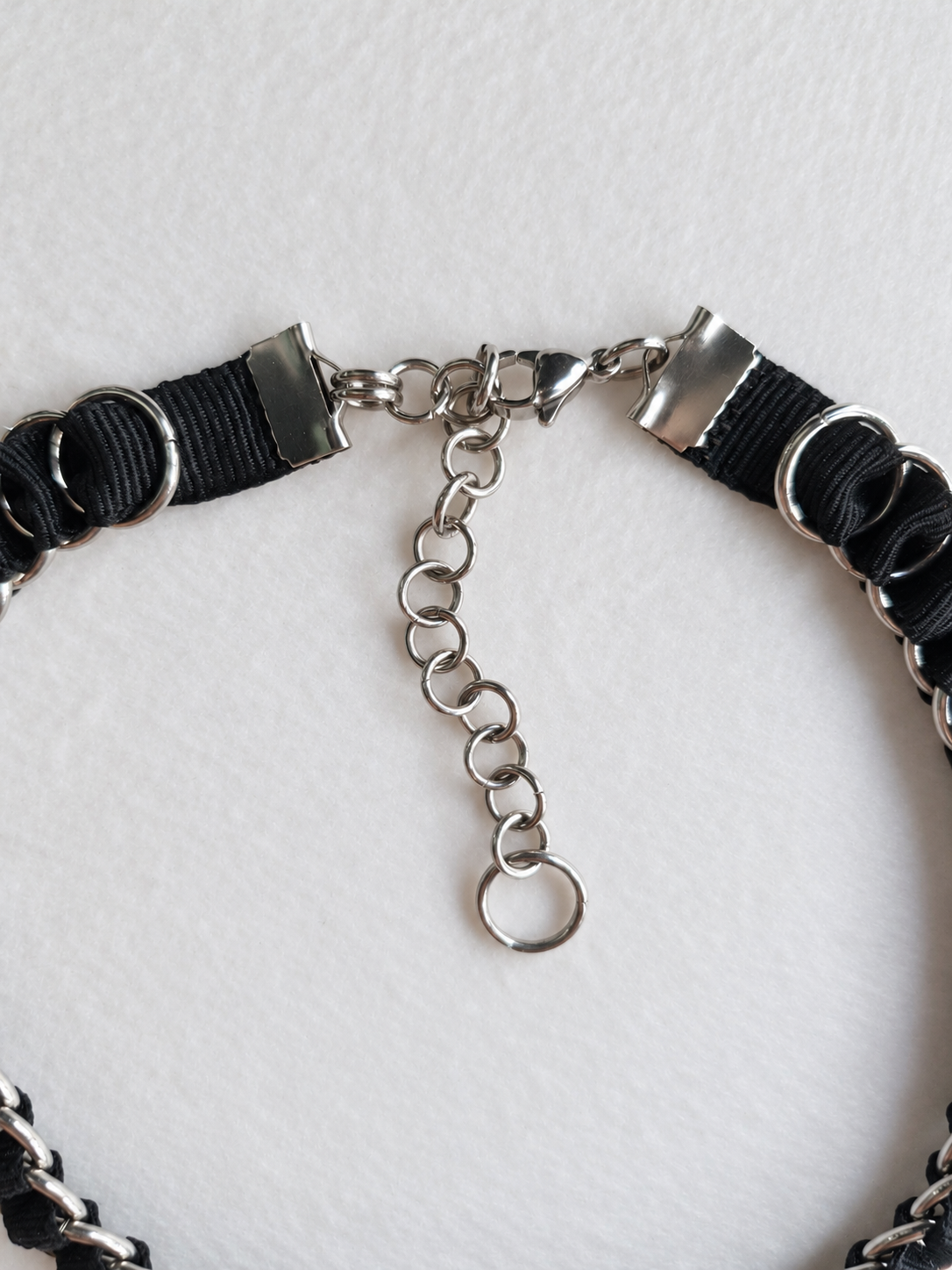 LOOM black choker fastening detail showing stainless steel ribbon clamps, clasp and adjustable extension chain.