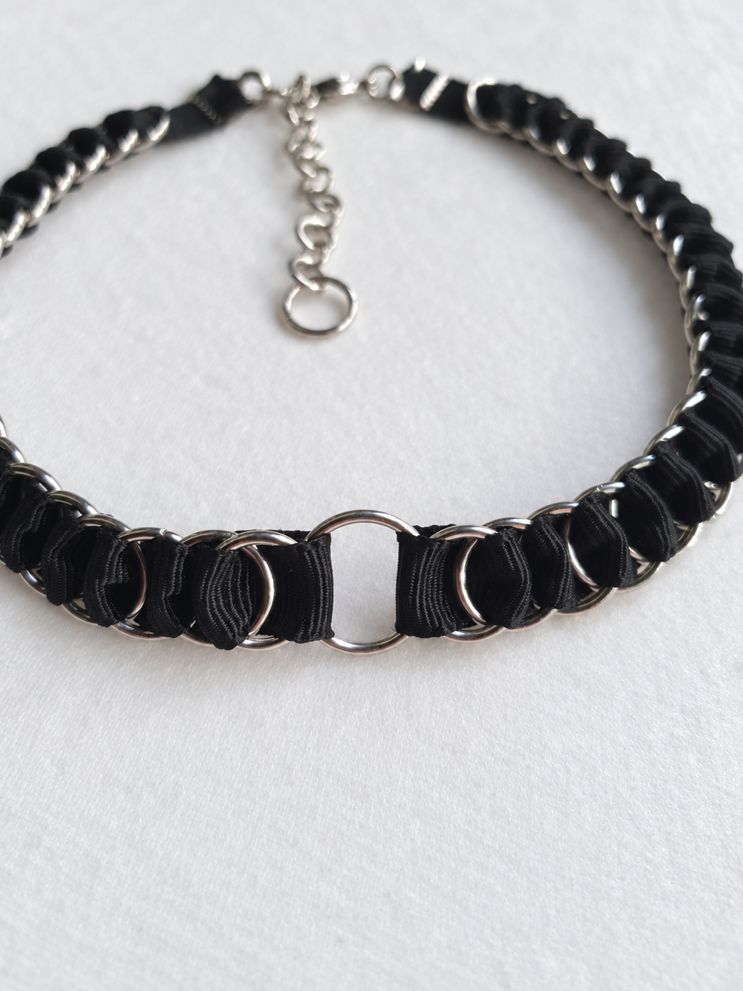 Close-up of the central stainless steel O-ring and black fabric ribbon weave on the LOOM choker.