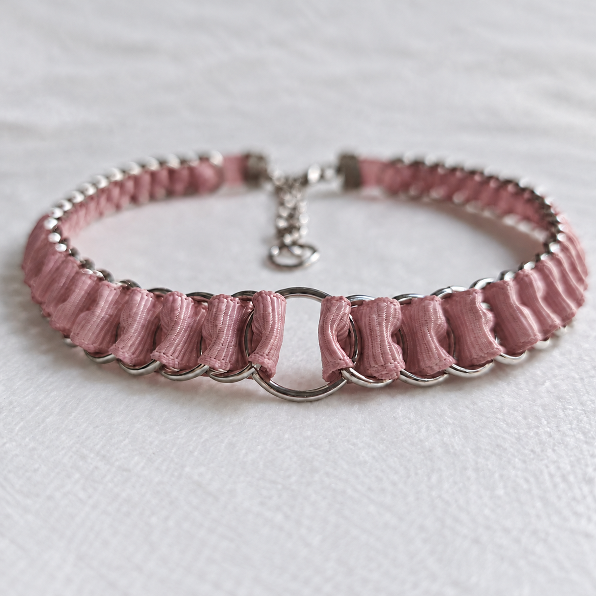 LOOM dusty pink fabric ribbon chainmail choker in a low front view, with stainless steel rings, a central O-ring and adjustable fastening on white fabric.