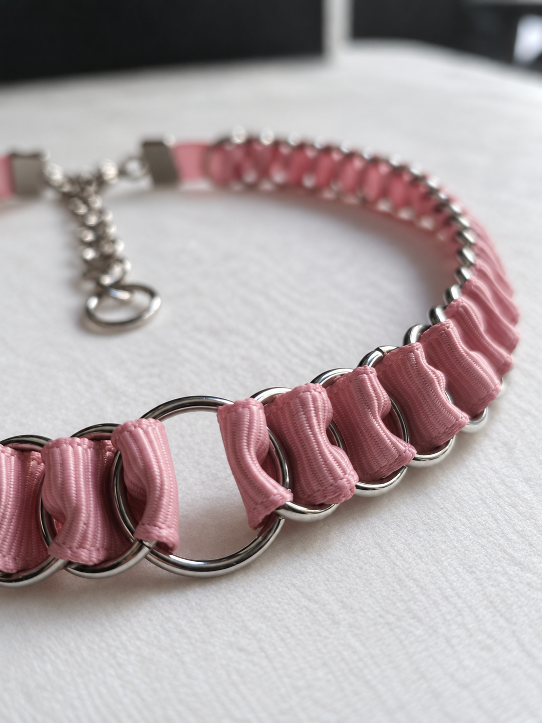 Close-up of the LOOM dusty pink ribbon weave and polished stainless steel rings beside the central O-ring.