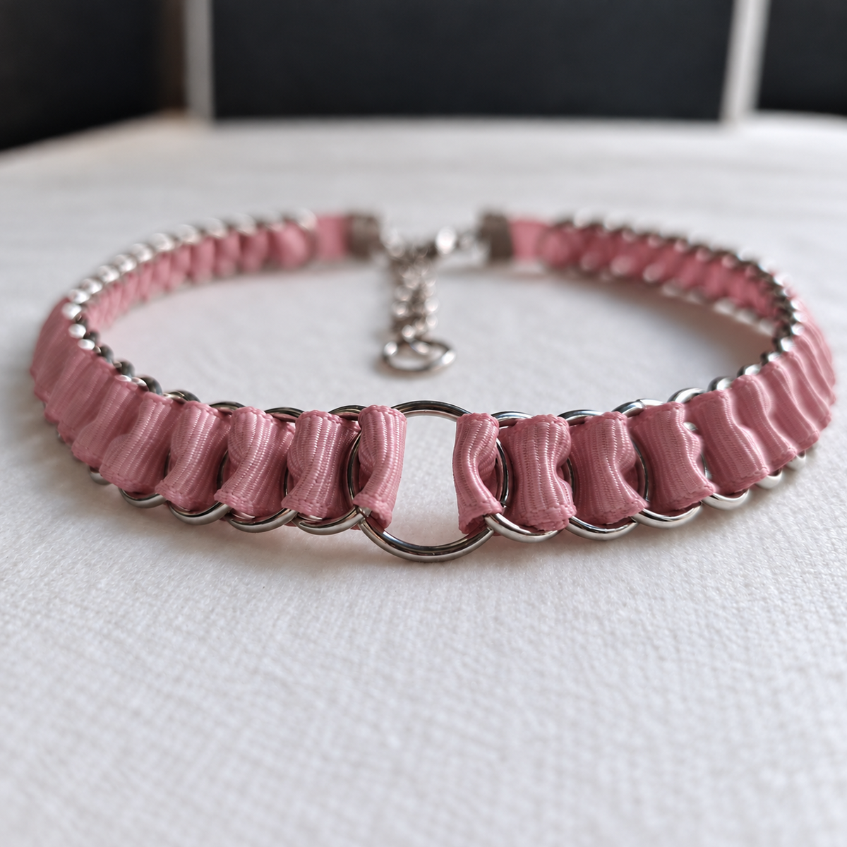 LOOM dusty pink ribbon chainmail choker with stainless steel rings and central O-ring, shown in a low front view on white fabric.