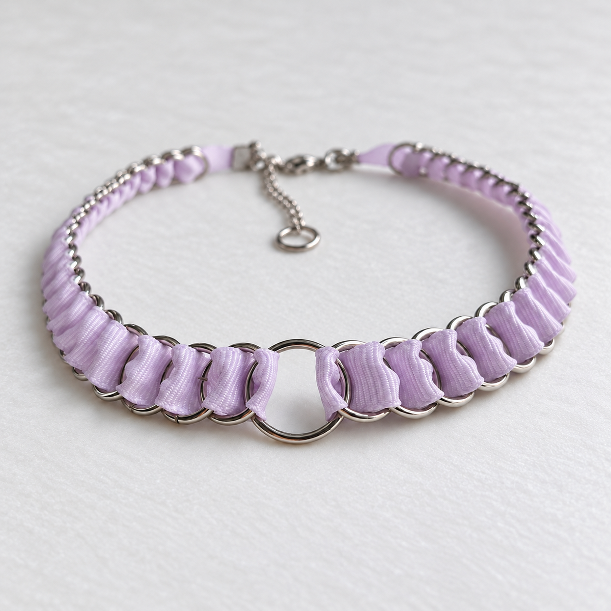 LOOM lilac fabric ribbon chainmail choker with polished stainless steel rings and a central O-ring, shown on white fabric.