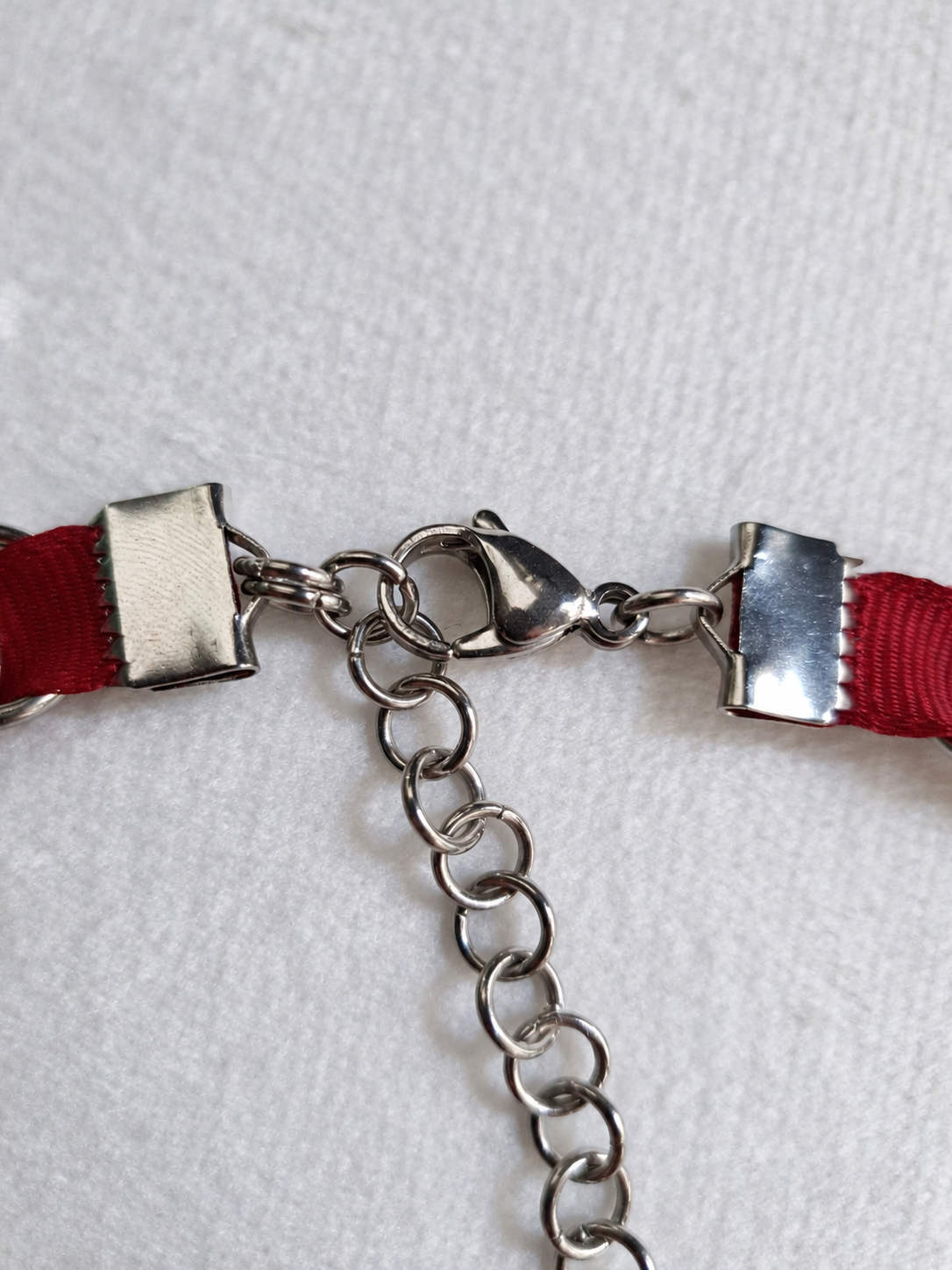 LOOM red choker fastening detail showing stainless steel ribbon clamps, lobster clasp and extension chain.