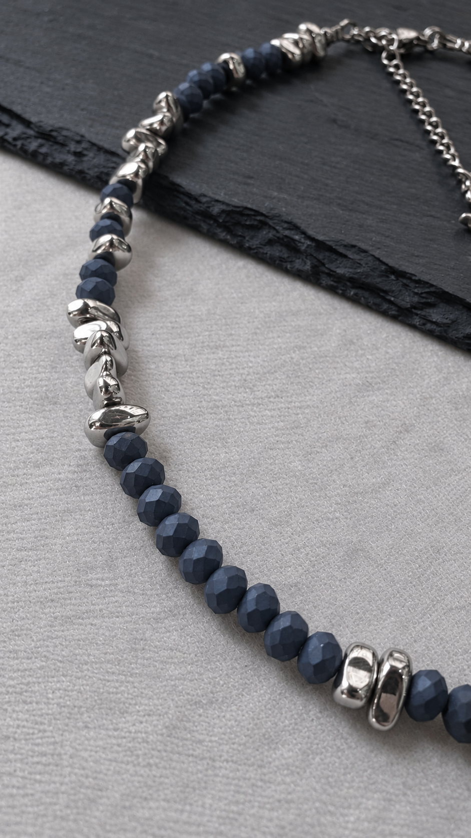 Side detail of NIGHTMARK showing groups of matte midnight blue crystal beads and irregular silver hematite beads leading to the rear closure.