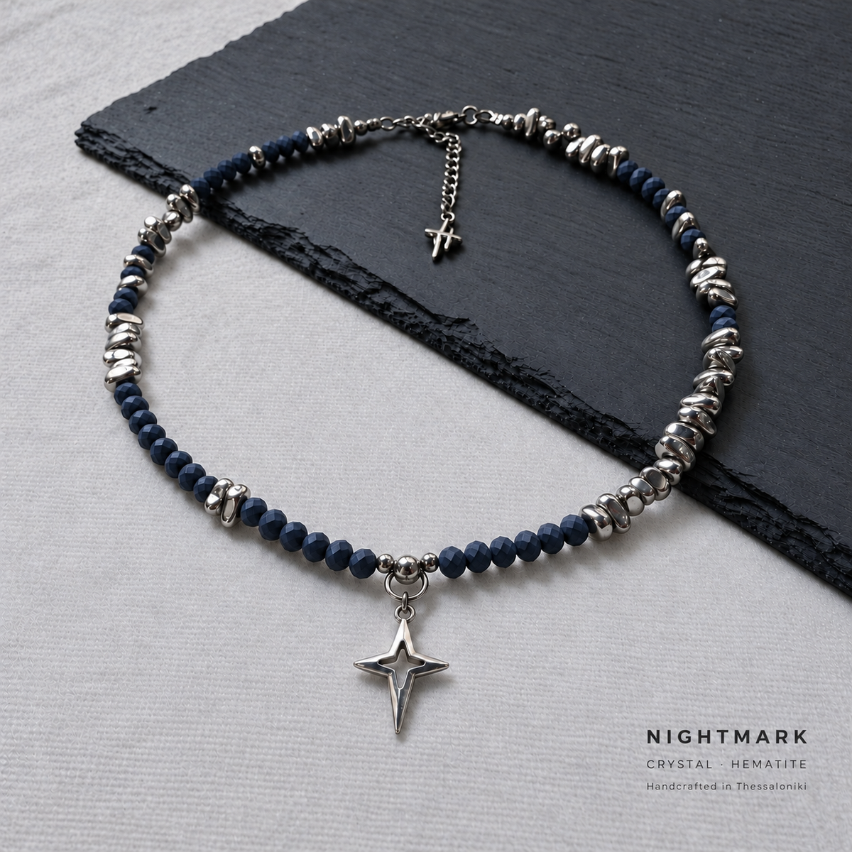 NIGHTMARK matte midnight blue crystal and silver hematite necklace with a silver-plated North Star pendant, with NIGHTMARK and materials text at the bottom right.