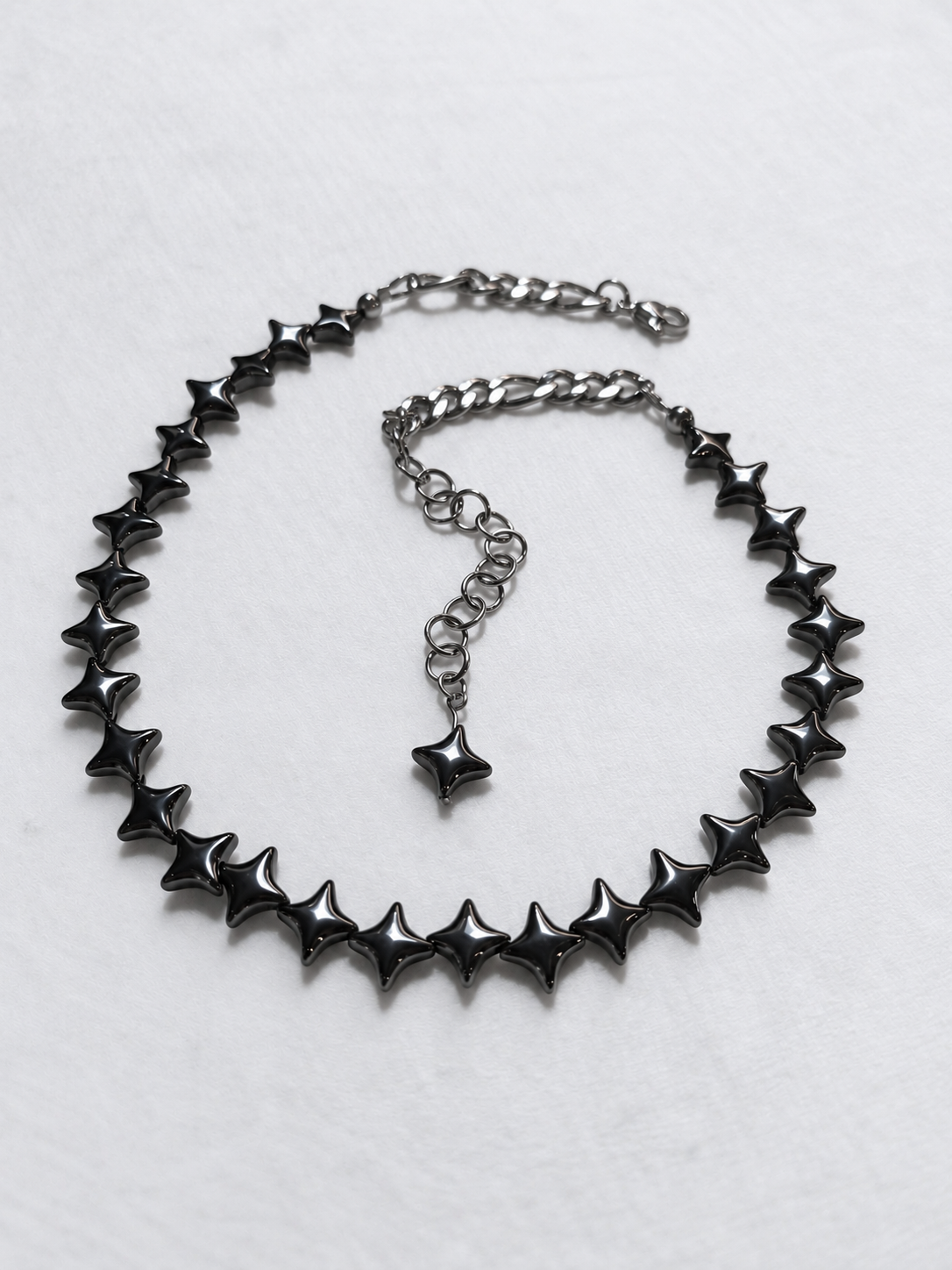 Angled view of NORTHLINE Gunmetal hematite star choker with stainless steel rear chains and star-tipped extension.