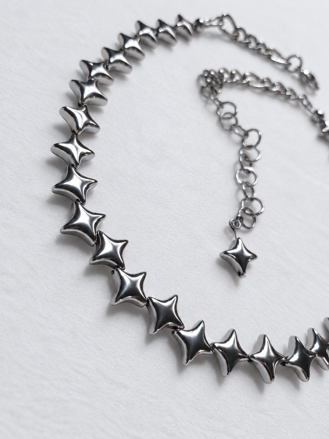 Close-up of polished silver North Star hematite beads on the NORTHLINE choker, with the stainless steel extension in the background.