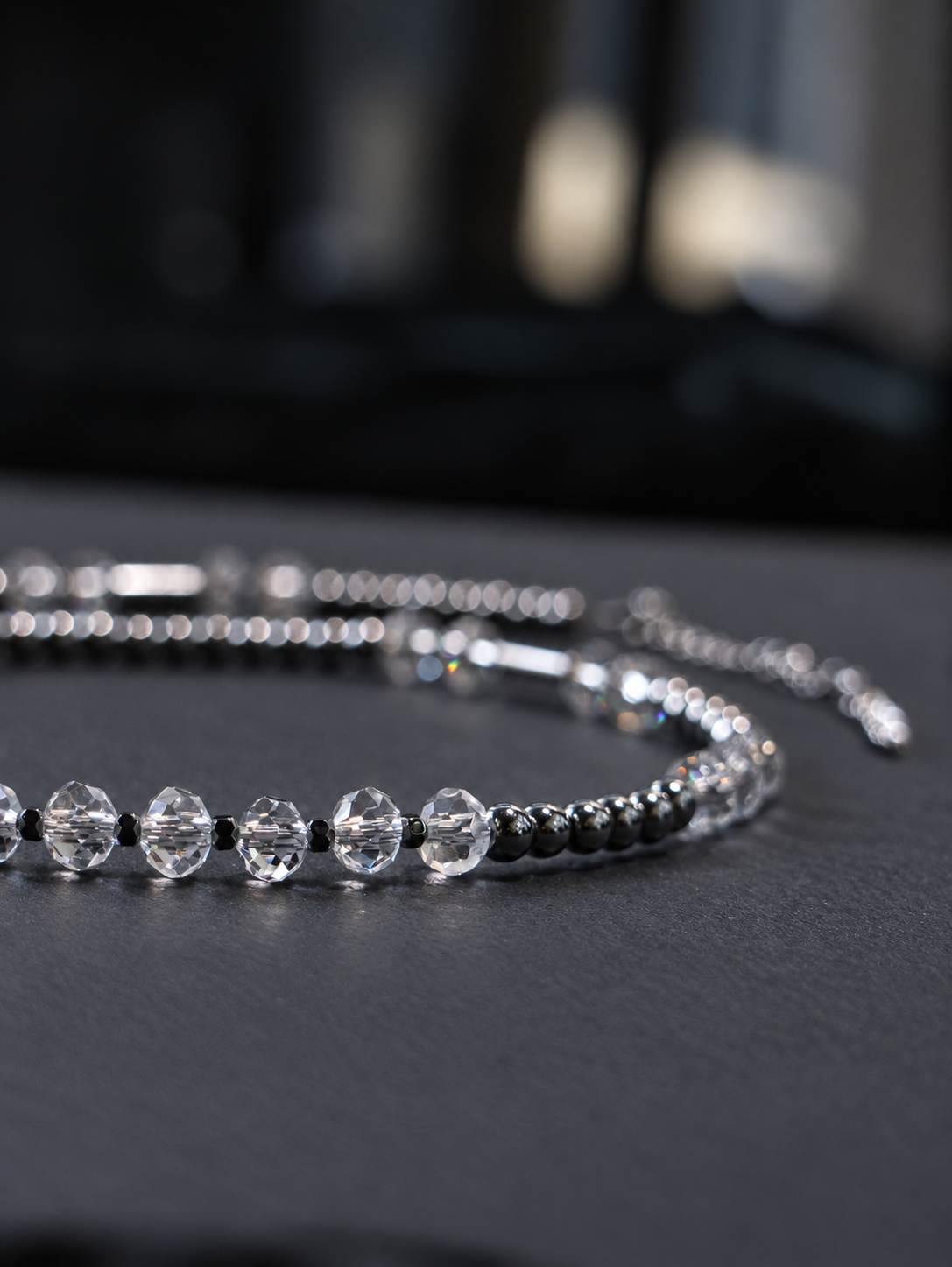 Detail of transparent faceted crystal beads separated by small polygon hematite spacers on the SPECTRAL ARC necklace.