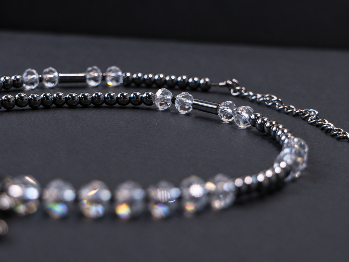 Low-angle close-up of SPECTRAL ARC's transparent faceted crystal beads, round silver hematite beads and tube hematite accents.
