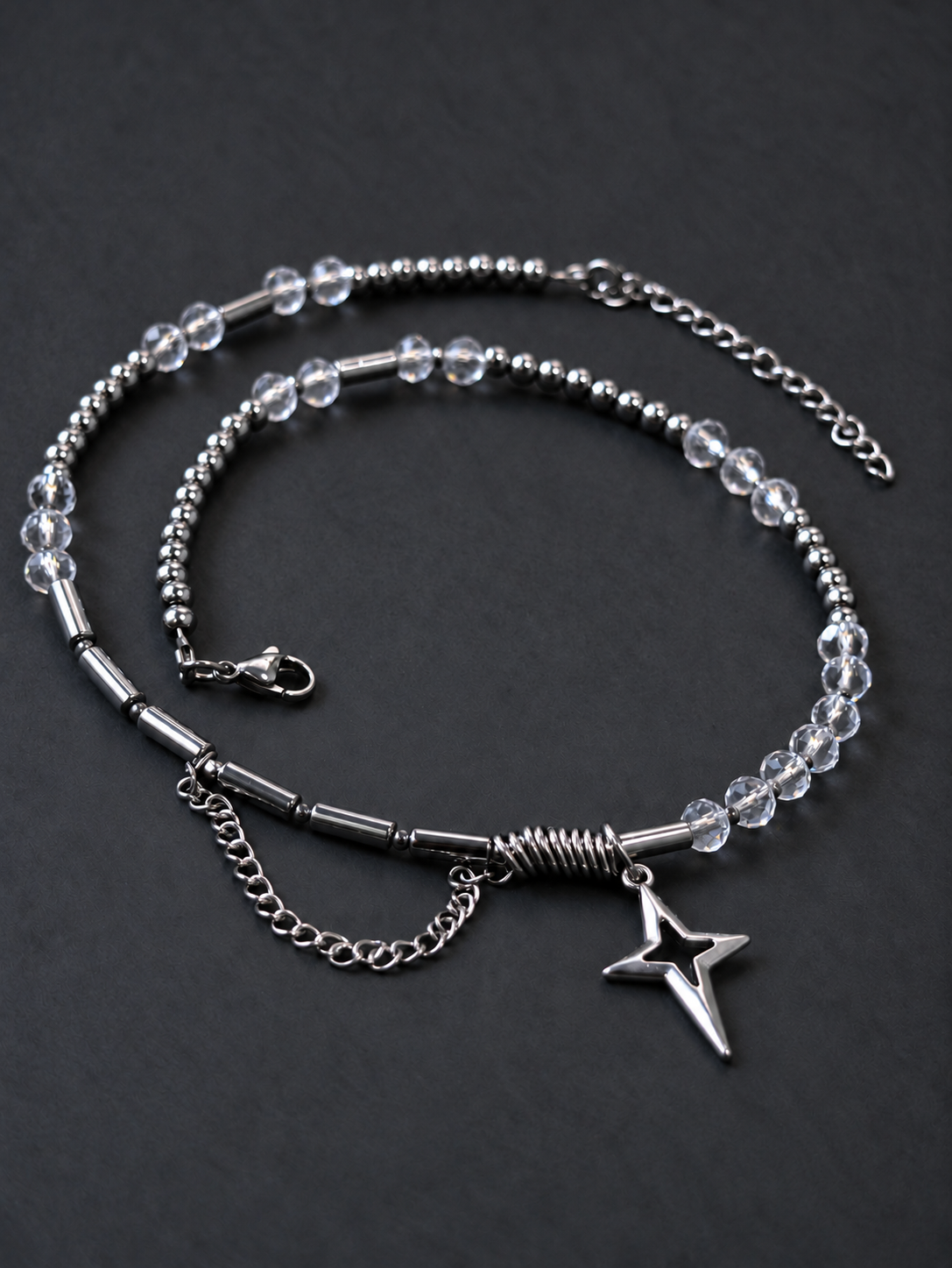 Full angled view of SPECTRAL ARC with transparent crystal beads, round and tube silver hematite beads, a North Star pendant and a draped stainless steel chain.