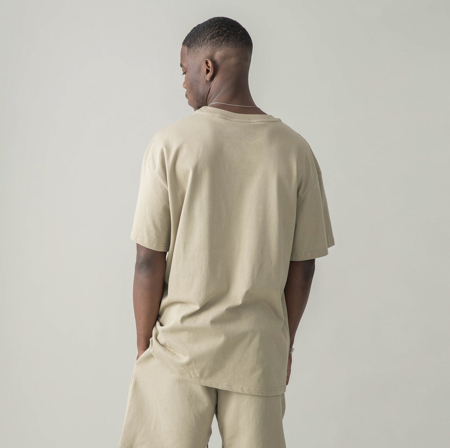 Back view of model in $MILE (BACK PRINT) - Unisex Oversized T-shirt (CAMEL)