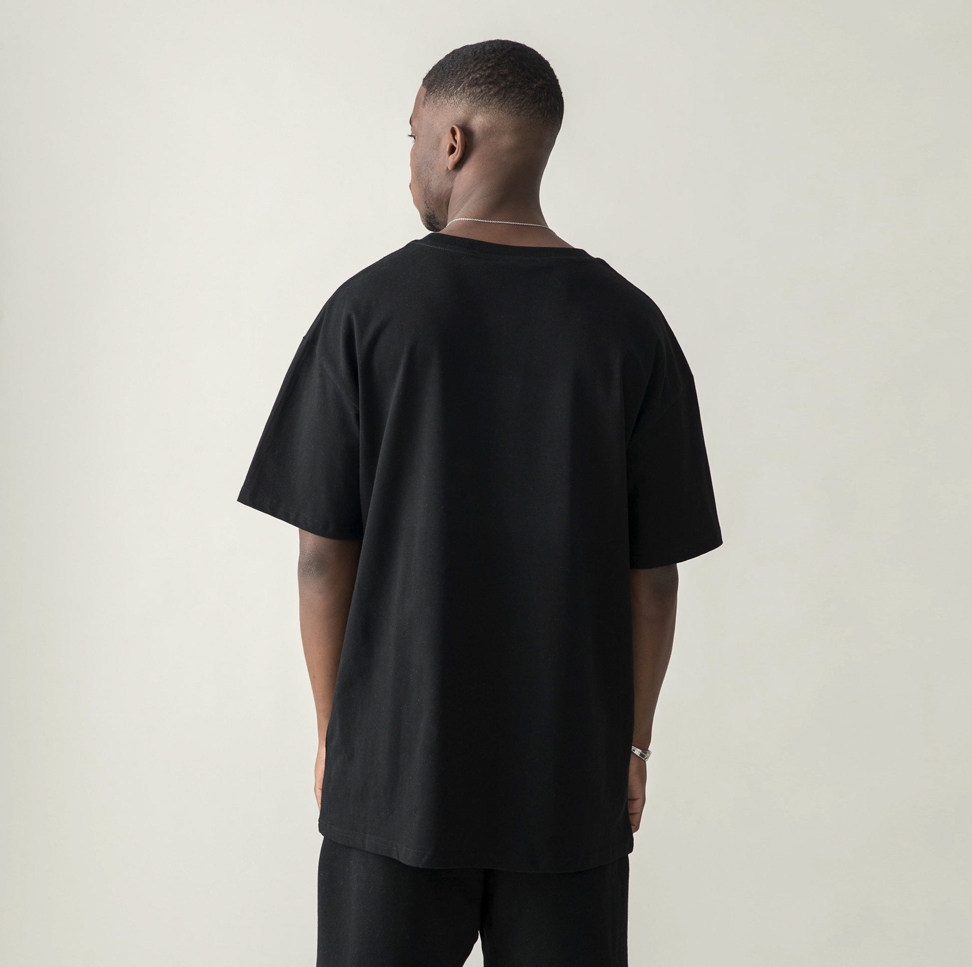 Back side of model in $MILE (BACK PRINT) - Unisex Oversized T-shirt black