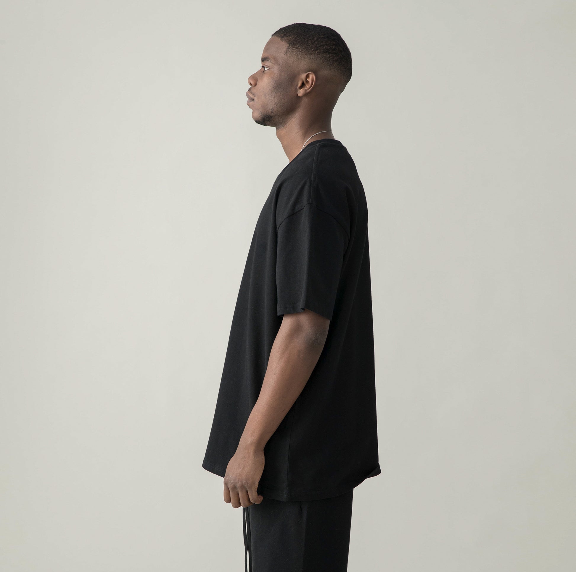 Side profile of model in $MILE (BACK PRINT) - Unisex Oversized T-shirt black