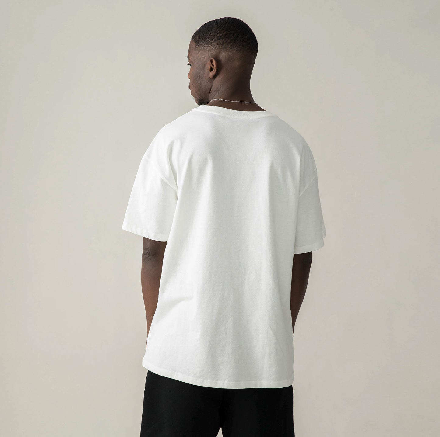 Back view of model in $MILE (BACK PRINT) - Unisex Oversized T-shirt (WHITE)
